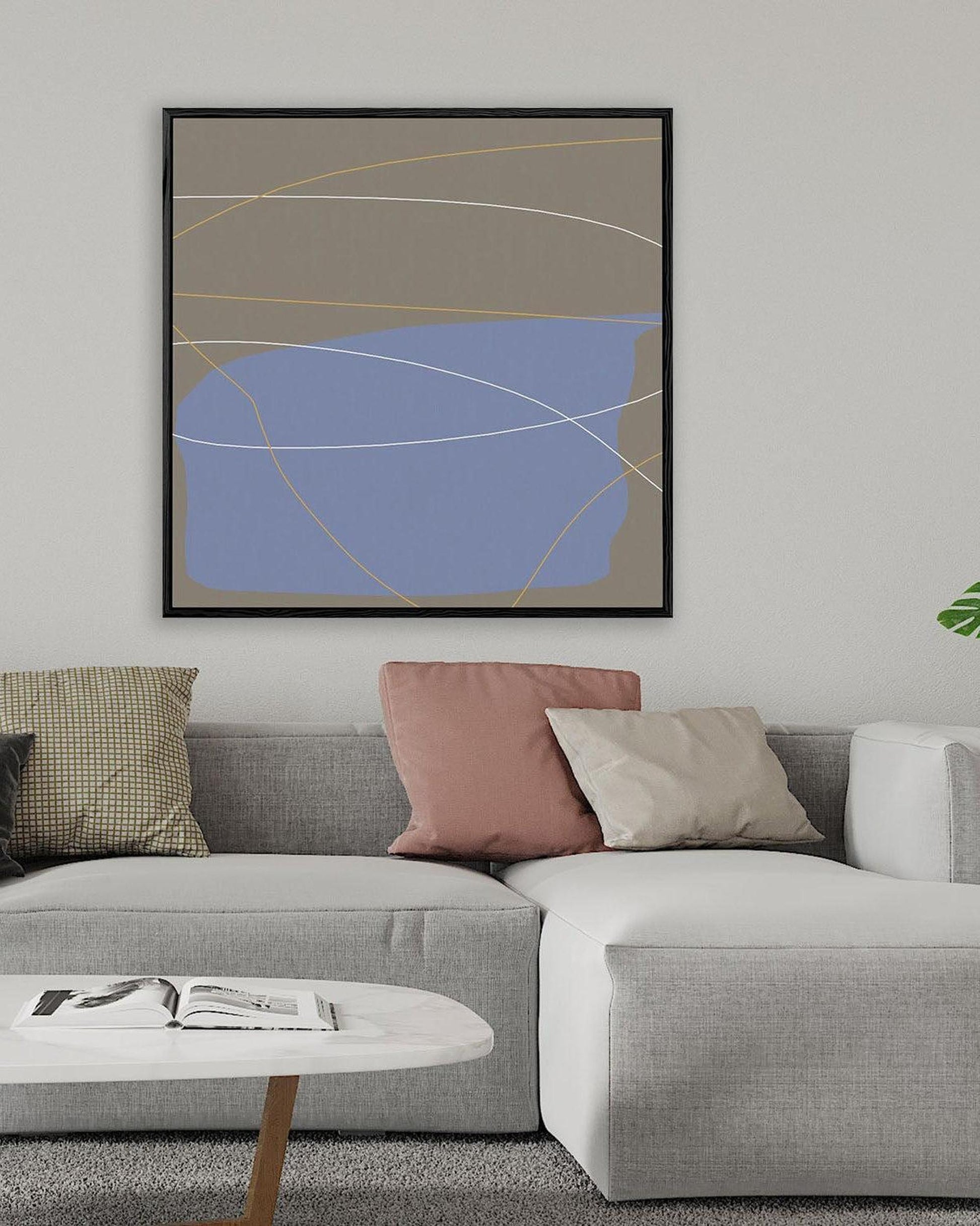 Gray sectional sofa with colorful pillows in a living room setting, featuring a framed abstract art piece on the wall.