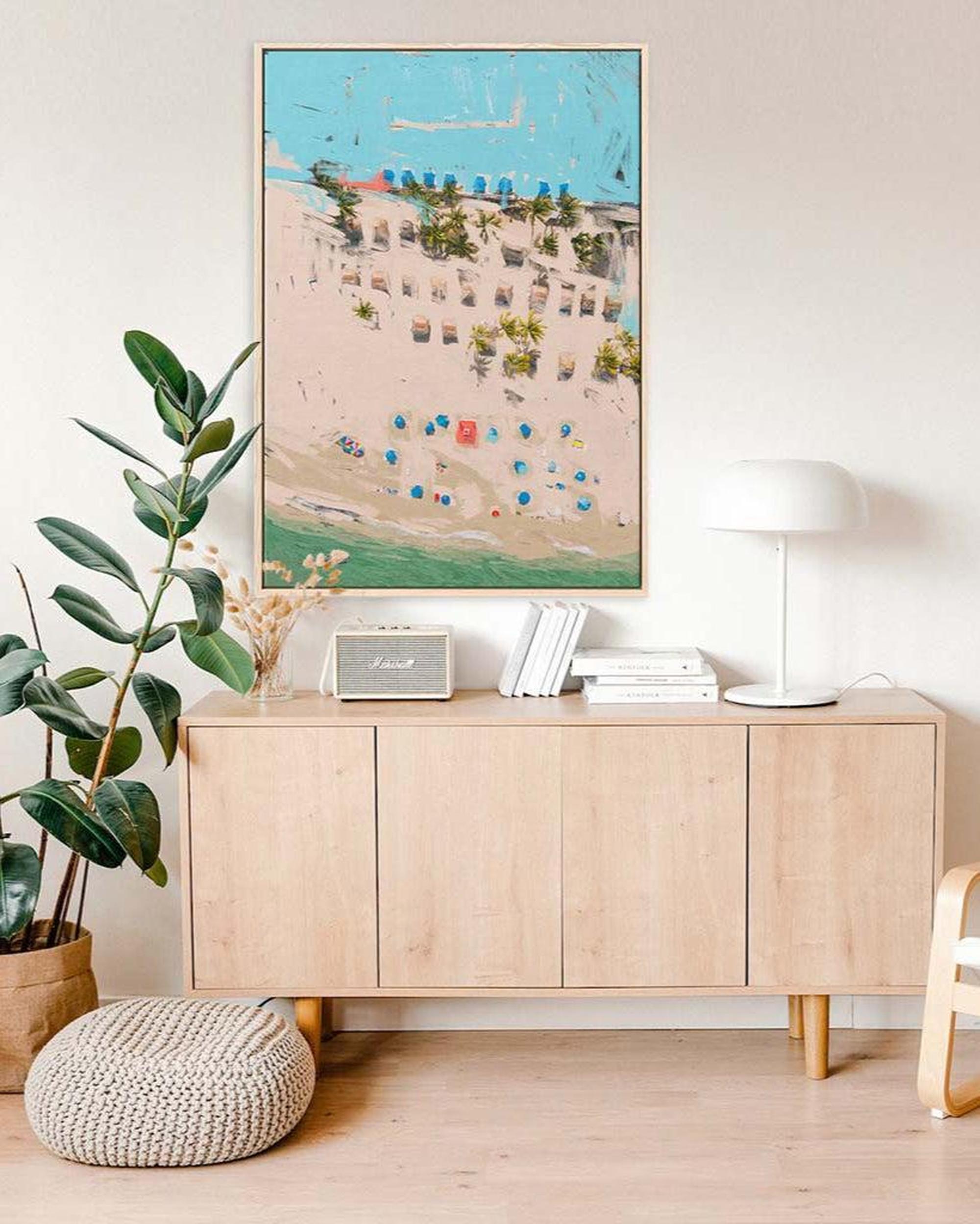 Light wood sideboard with decorative items in a room with a large framed artwork on the wall.