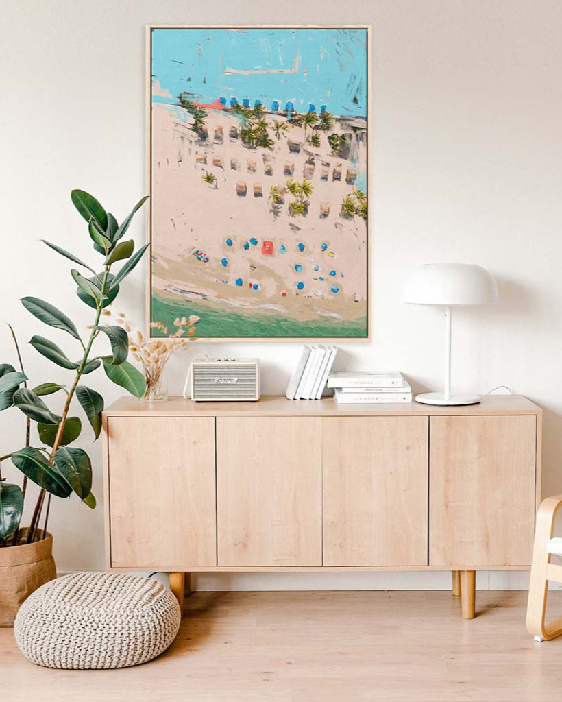 Light wood sideboard with decorative items in a room with a large framed artwork on the wall.