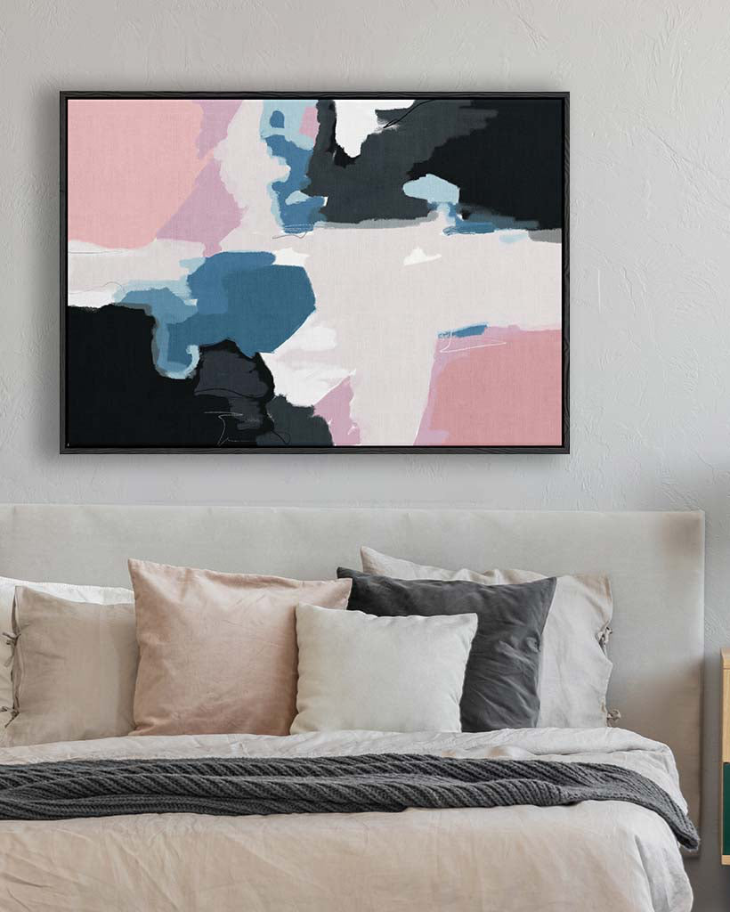Abstract art print on a wall above a bed with pillows