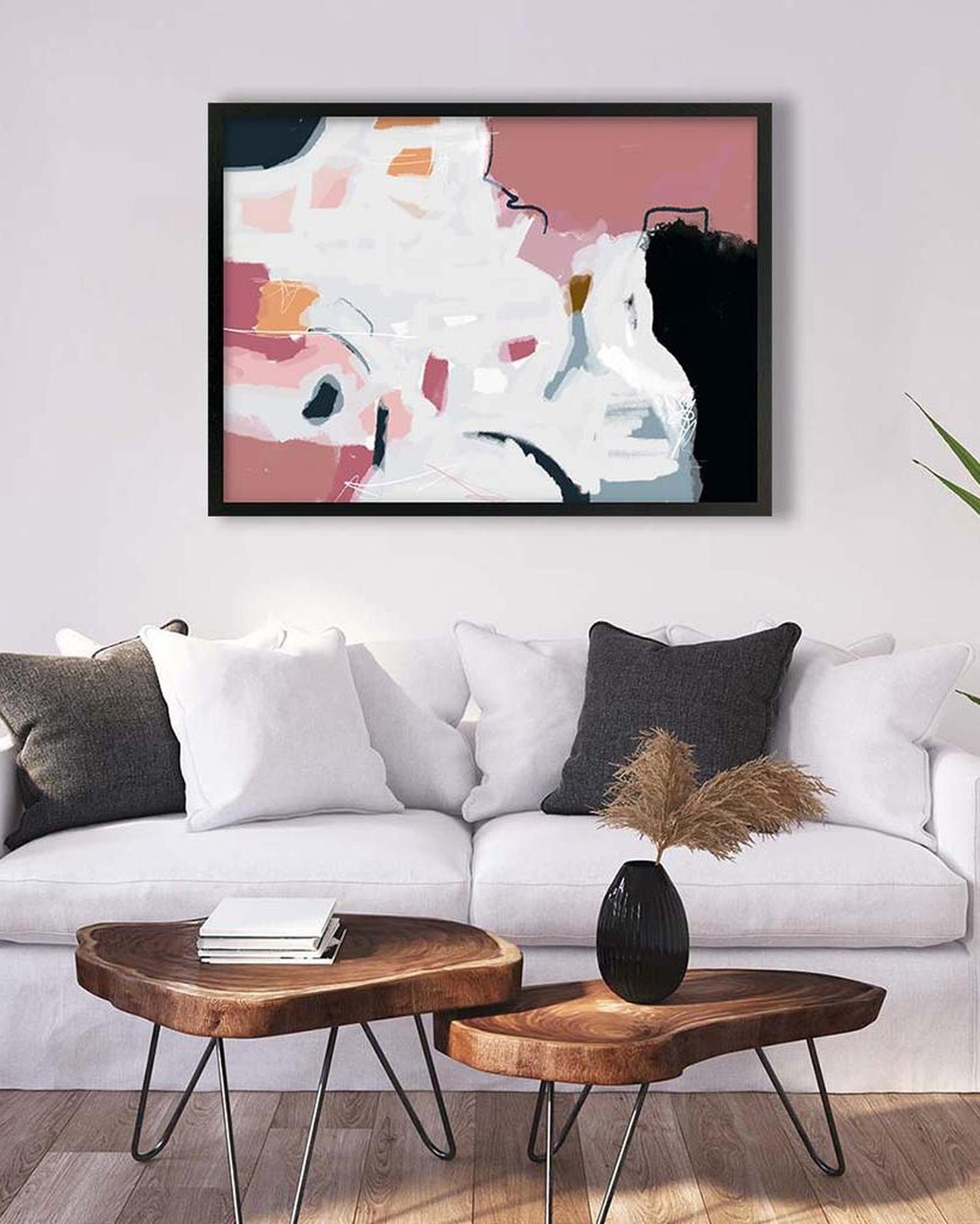 Modern living room with abstract art, white sofa, and wooden coffee table.