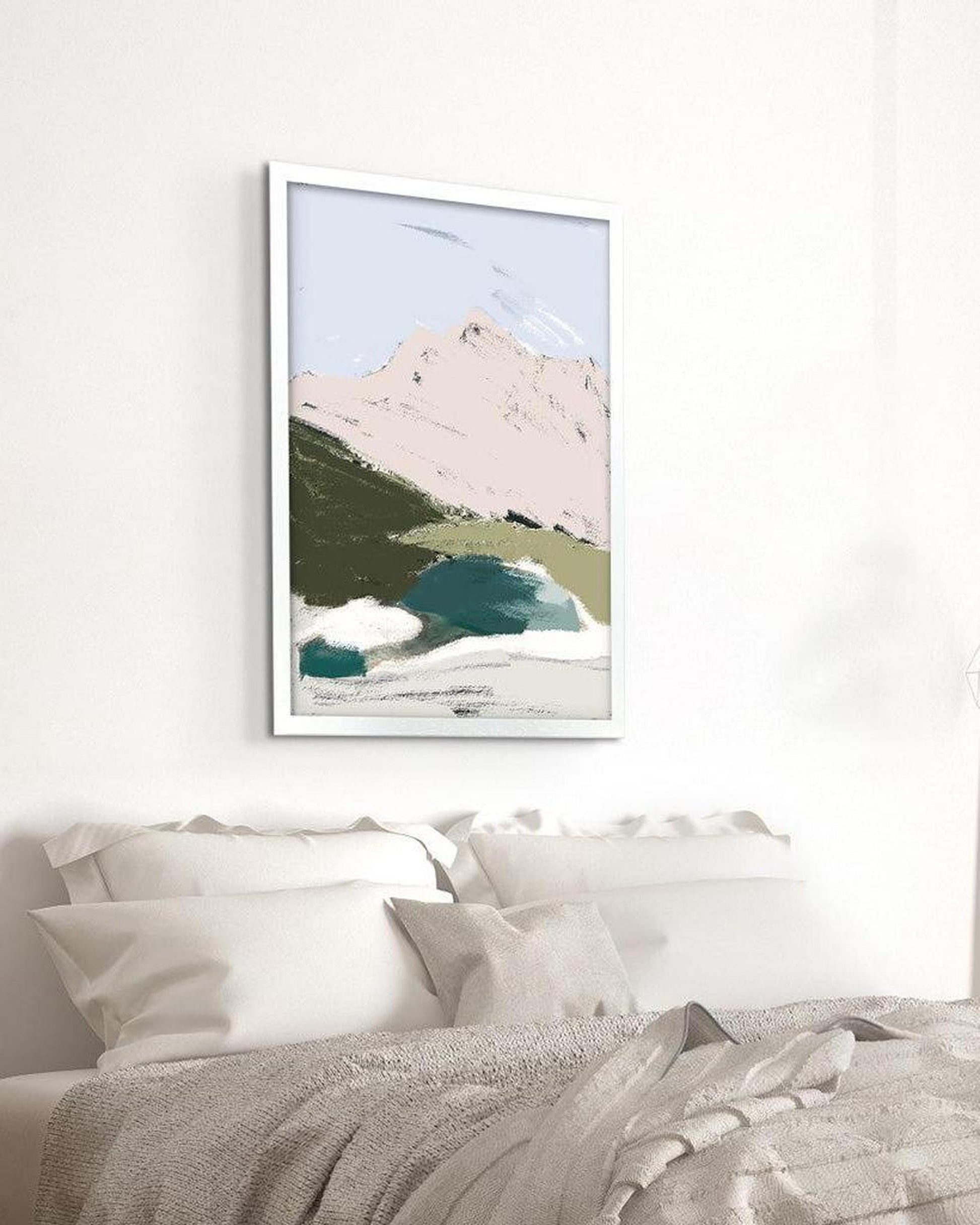 Framed artwork of a mountain landscape above a bed with white bedding.