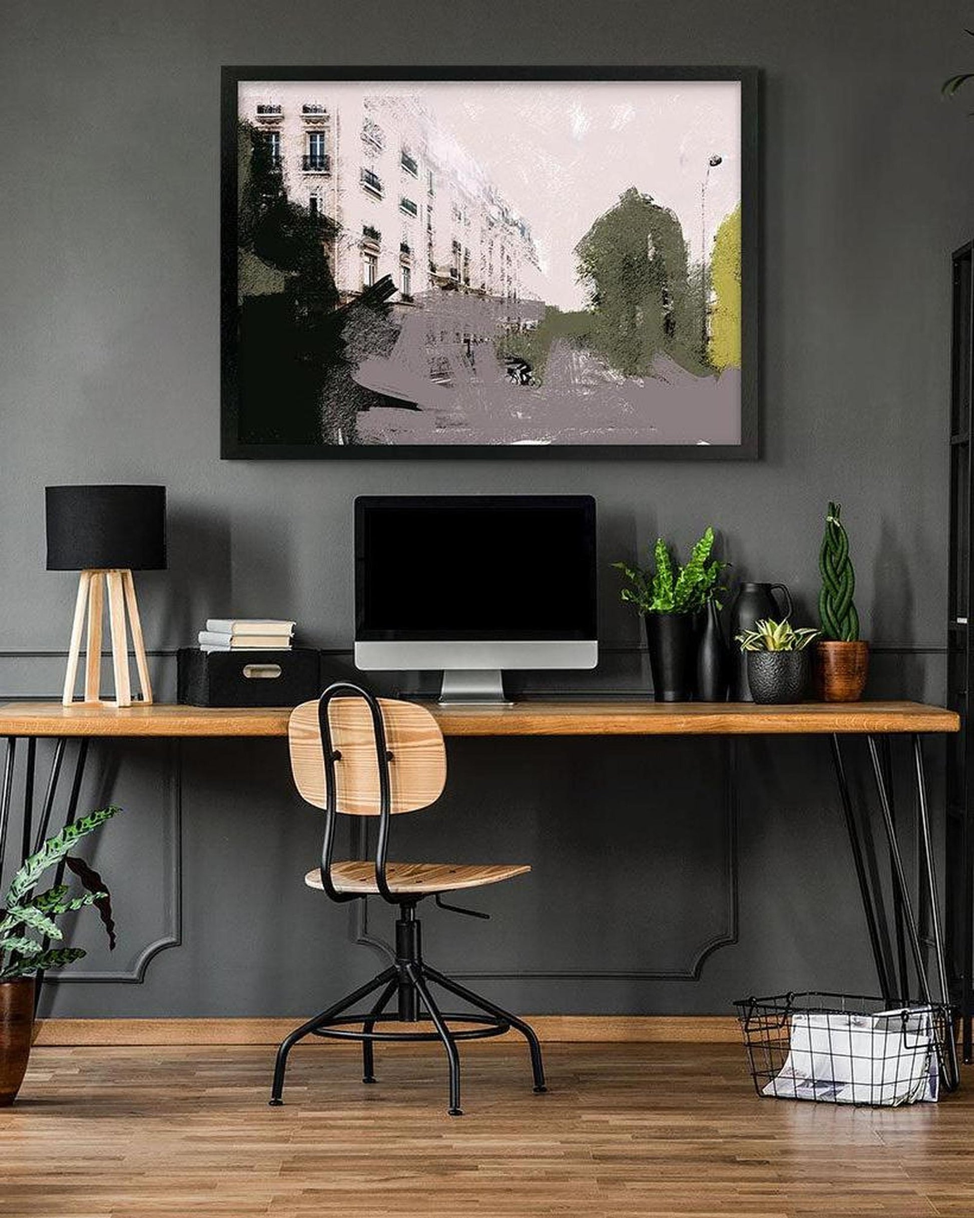 Modern home office with wooden desk, chair, and framed artwork on a gray wall.