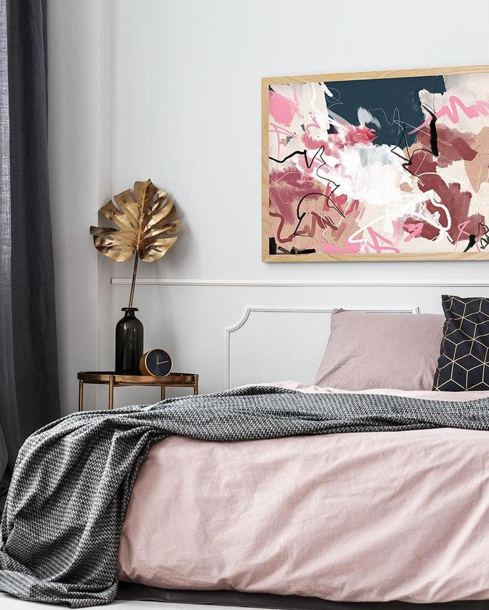 Bedroom with abstract art on the wall, pink bedding, and decorative elements.