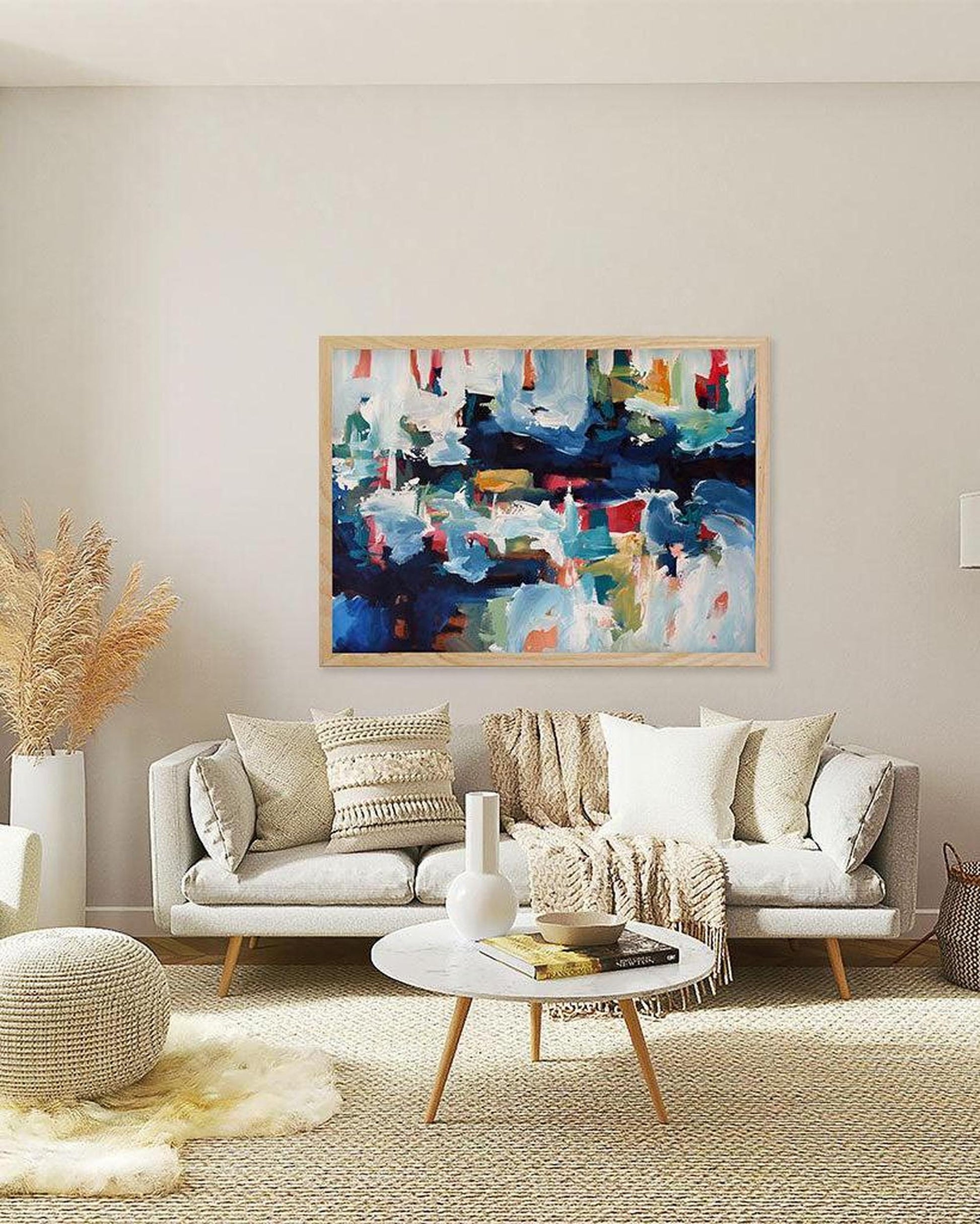 Living room with a gray sofa, abstract painting, and decorative items.
