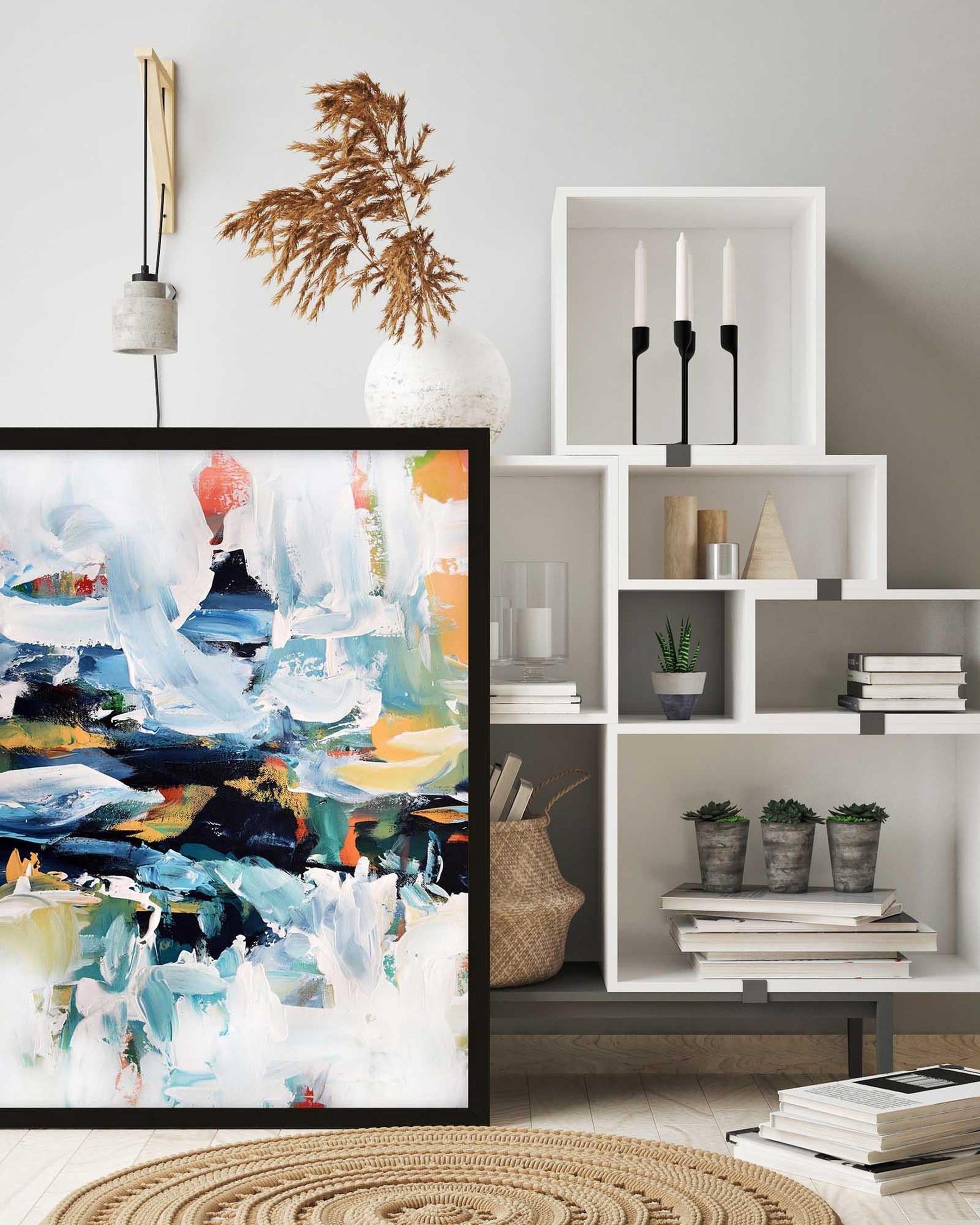 Living room with abstract painting, white bookshelf, and decorative items.