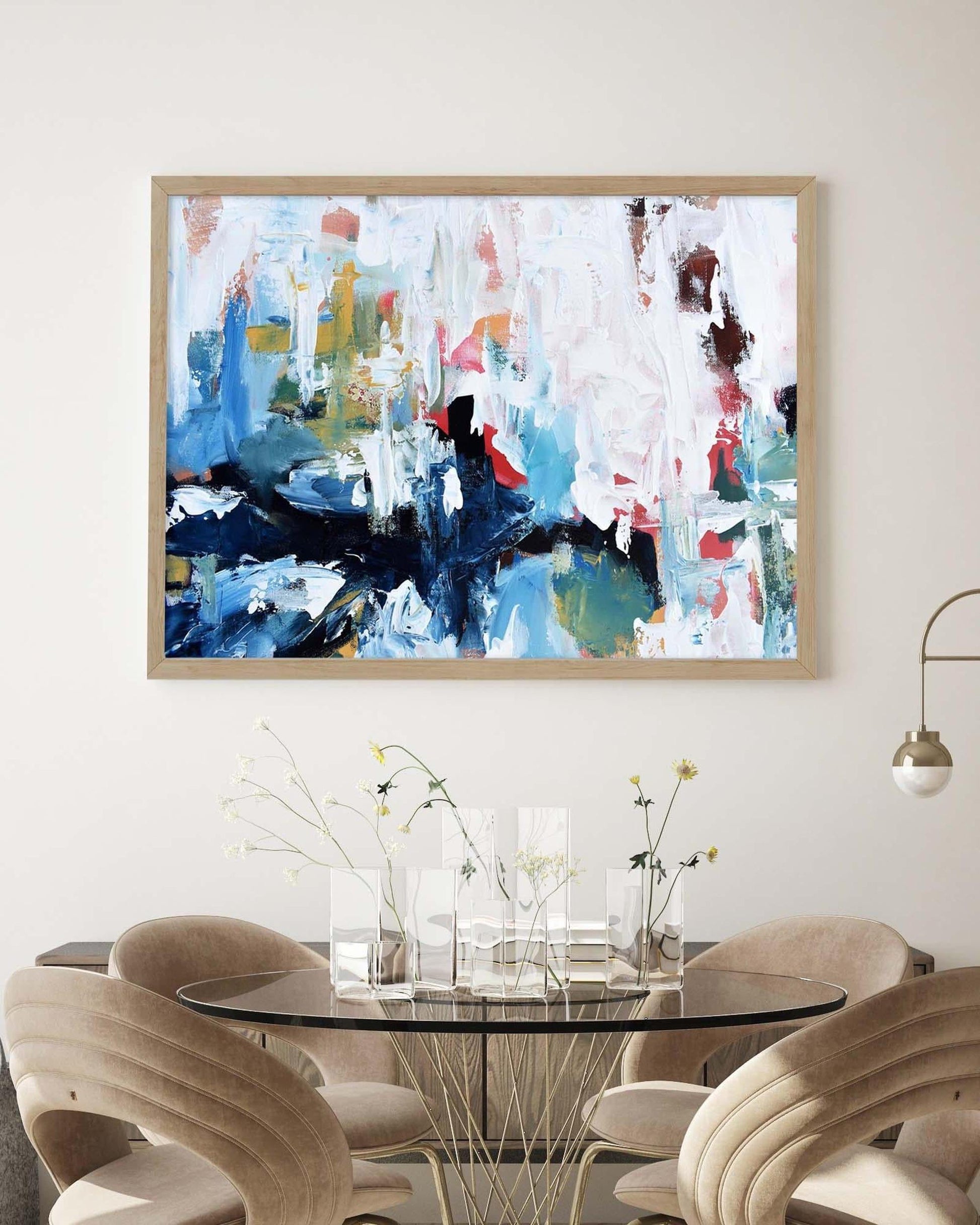 Abstract painting on a wall above a dining table with modern chairs.