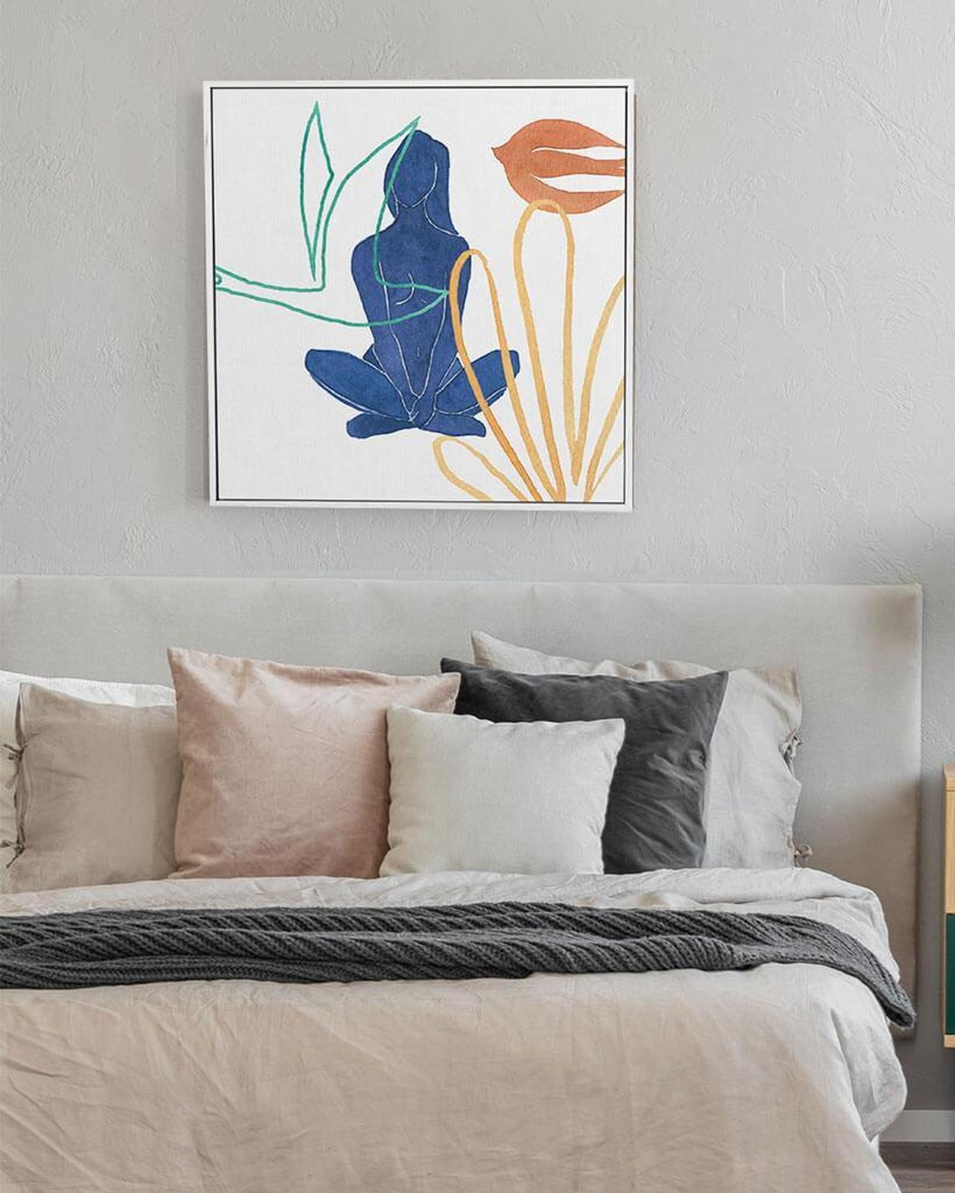 Framed abstract art above a bed with neutral bedding