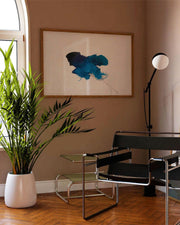 Modern interior with a plant, chairs, and a painting on the wall.
