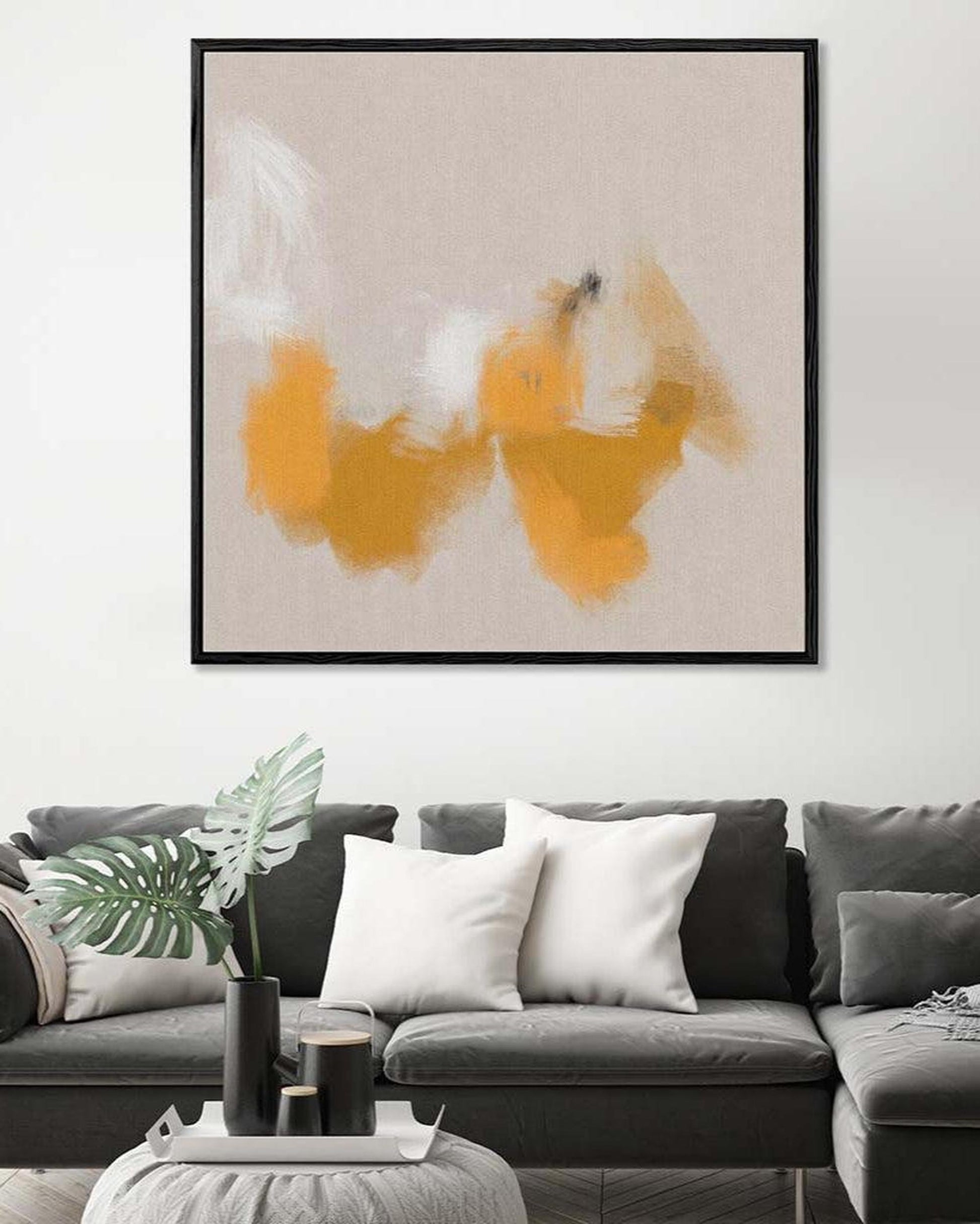 Abstract art piece with orange and white colors on a gray sofa and white wall background