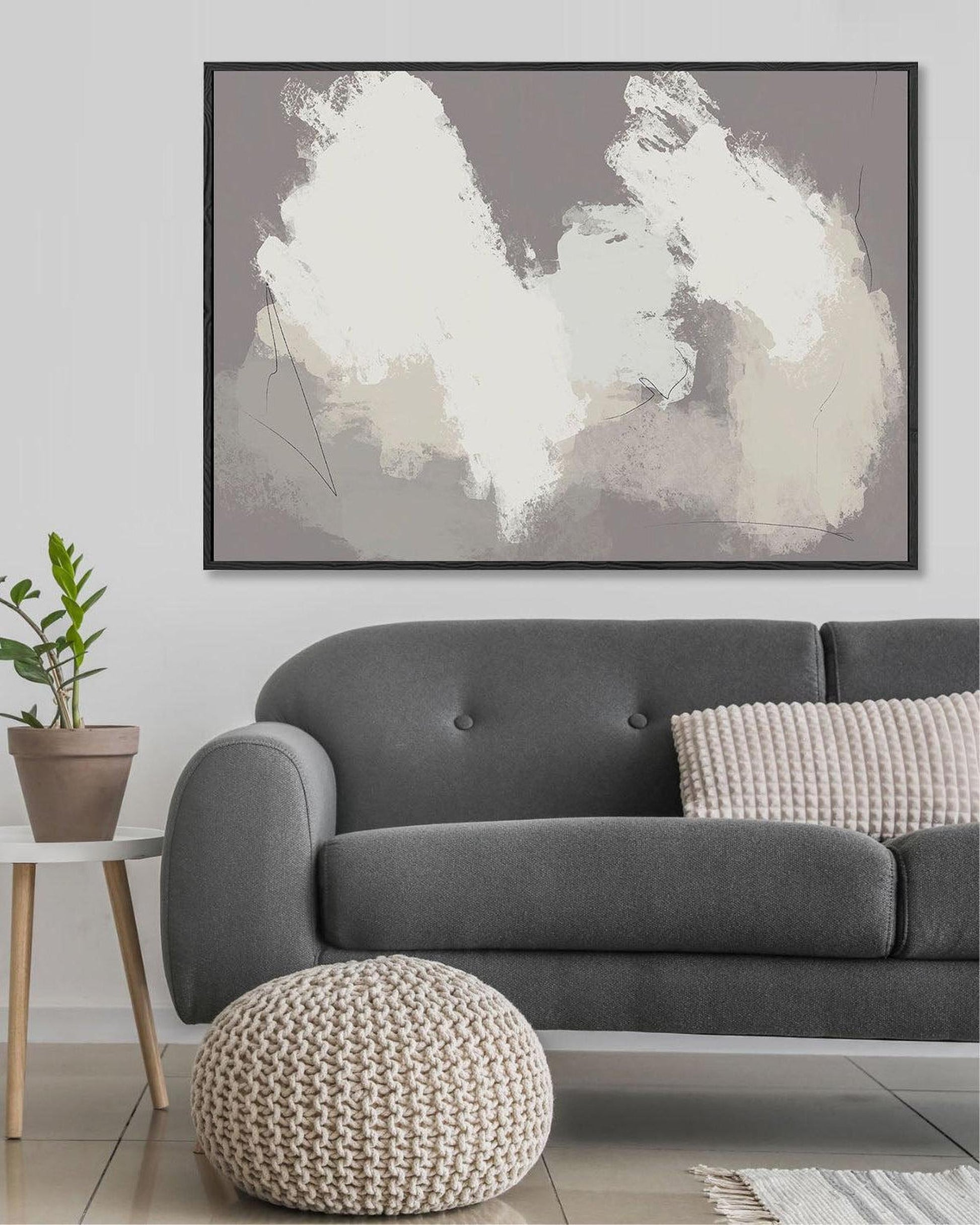 Gray sofa with a textured pouf and abstract art in a living room setting