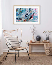 Abstract art print on a wall above a chair in a room with decor elements.
