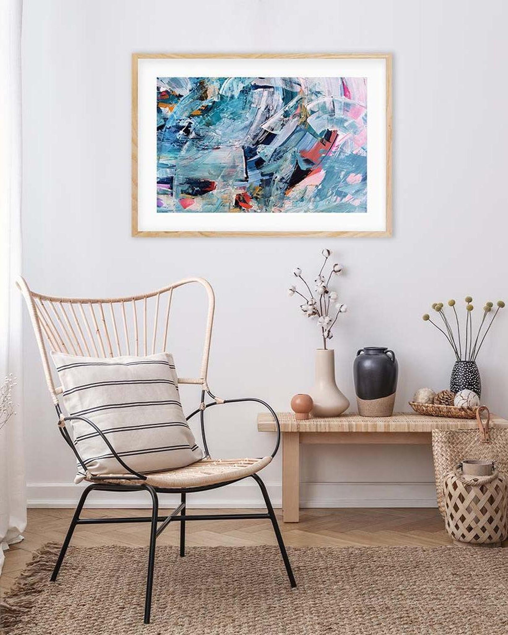 Abstract art print on a wall above a chair in a room with decor elements.