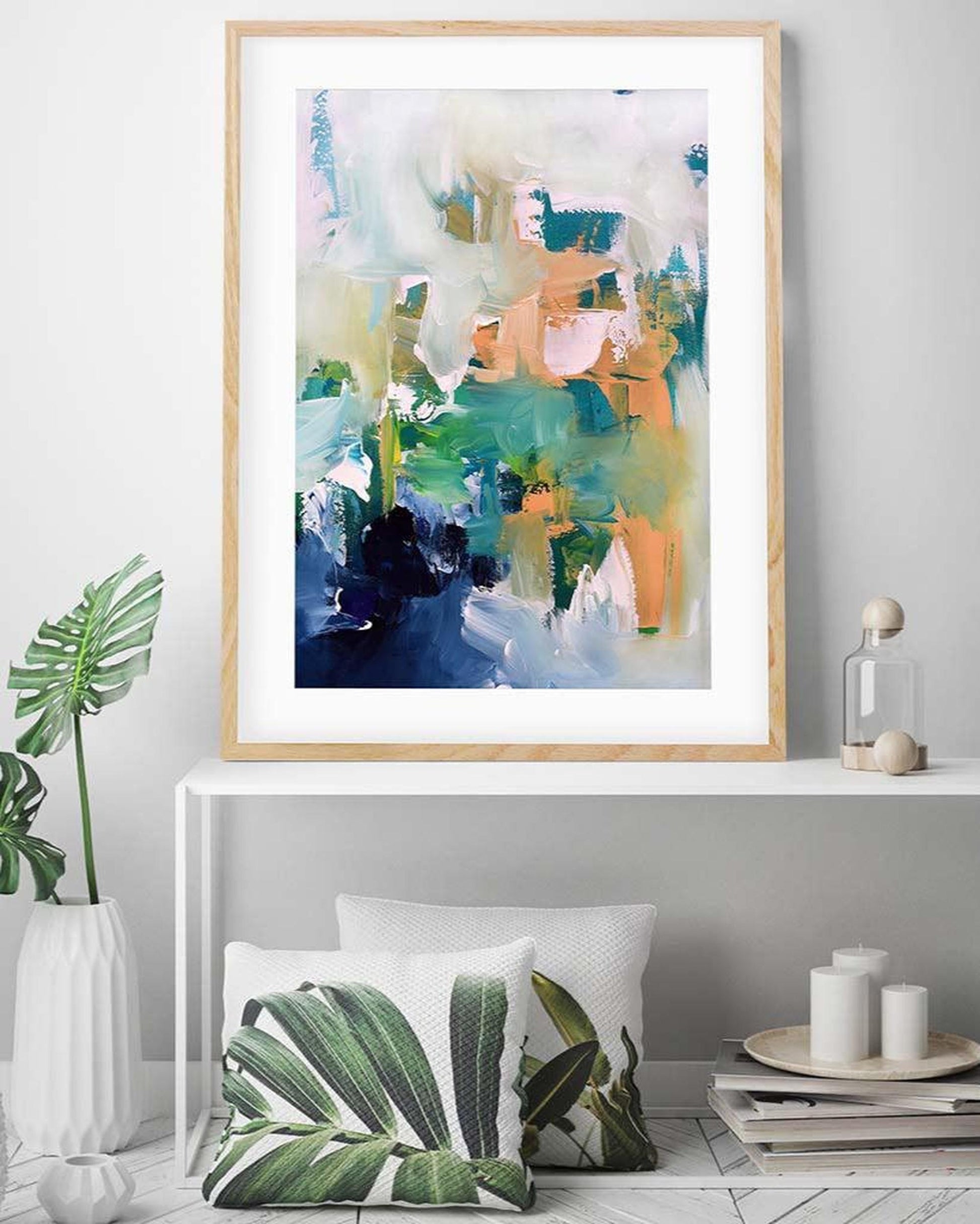 Framed abstract art piece on a wall above a white console table with decorative items.