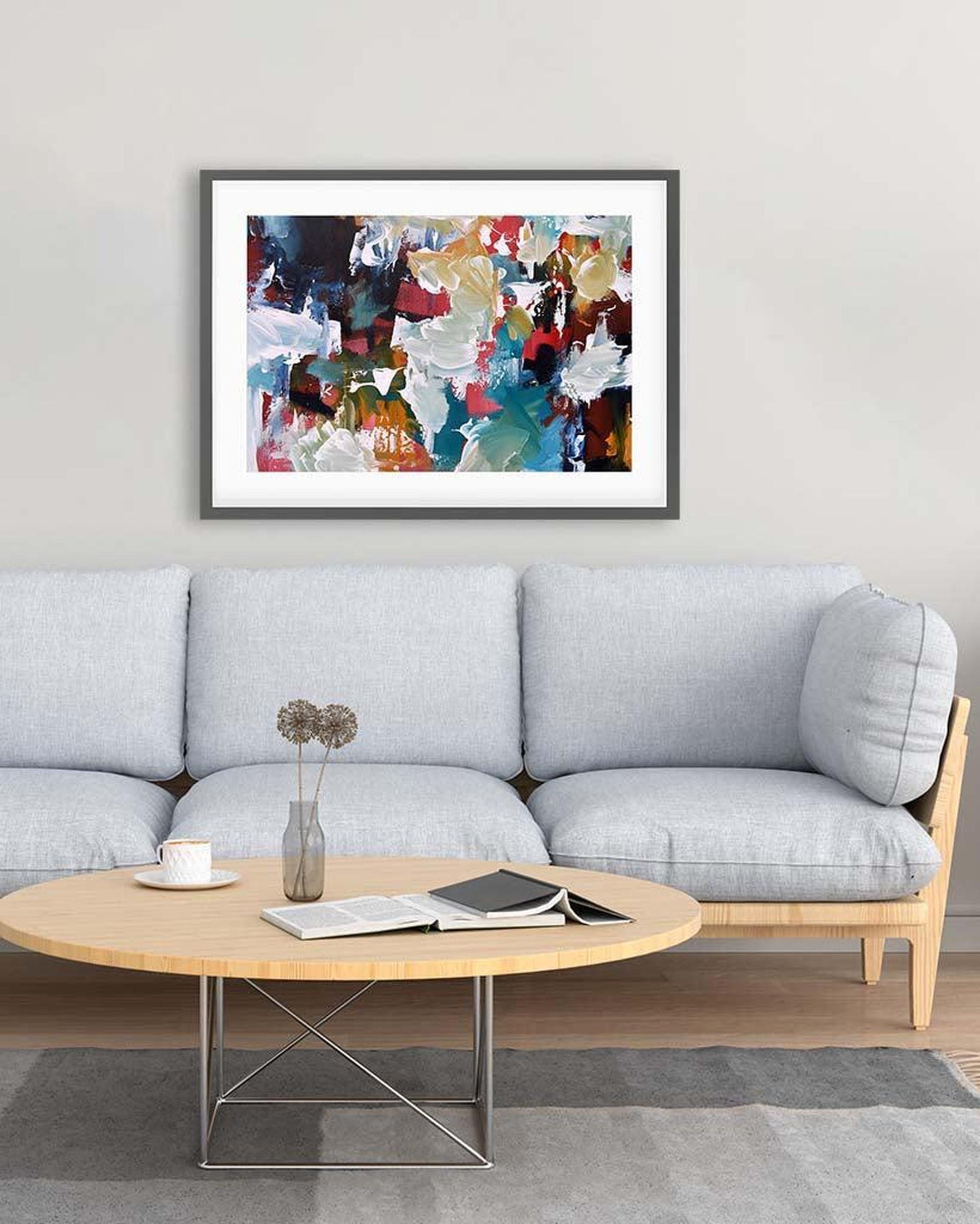 Living room with a gray sofa, round wooden coffee table, and abstract art on the wall.
