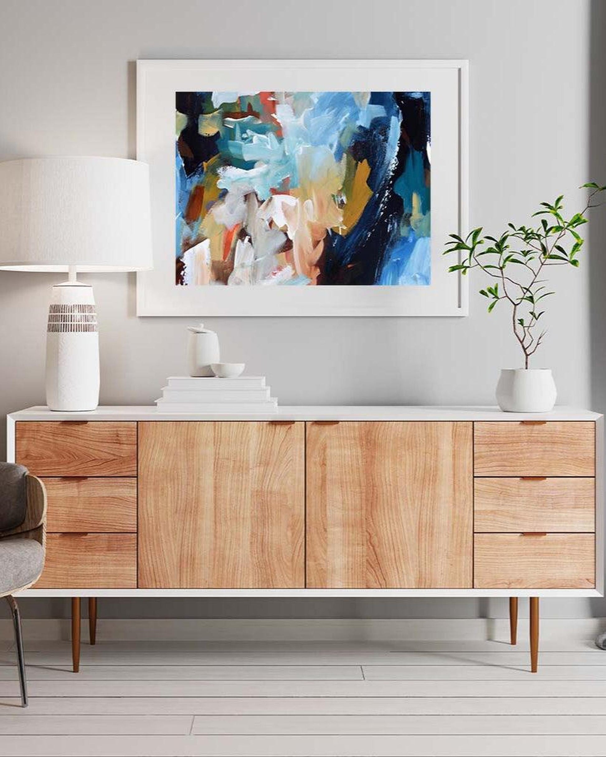Wooden sideboard with abstract art above it in a modern interior setting.