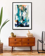 Abstract art print on a wall above a wooden dresser with decorative items.