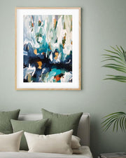 Framed abstract art on a wall above a bed with green and beige pillows.