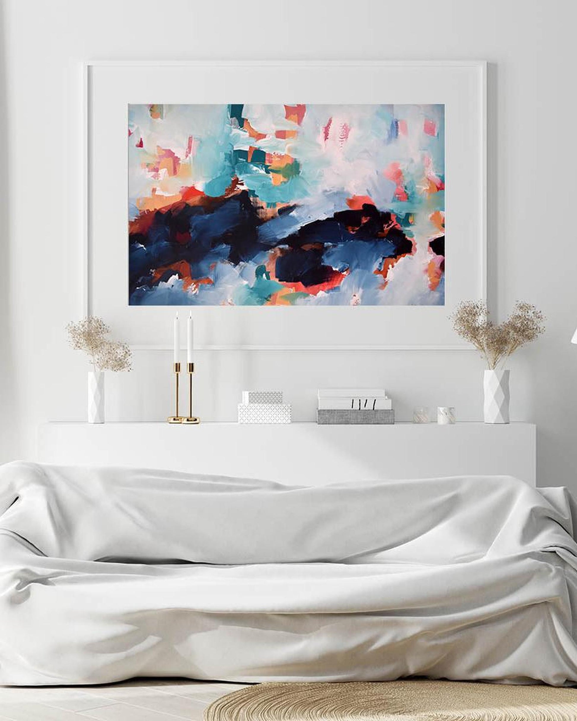 Abstract painting on a wall above a white sofa with decorative elements.