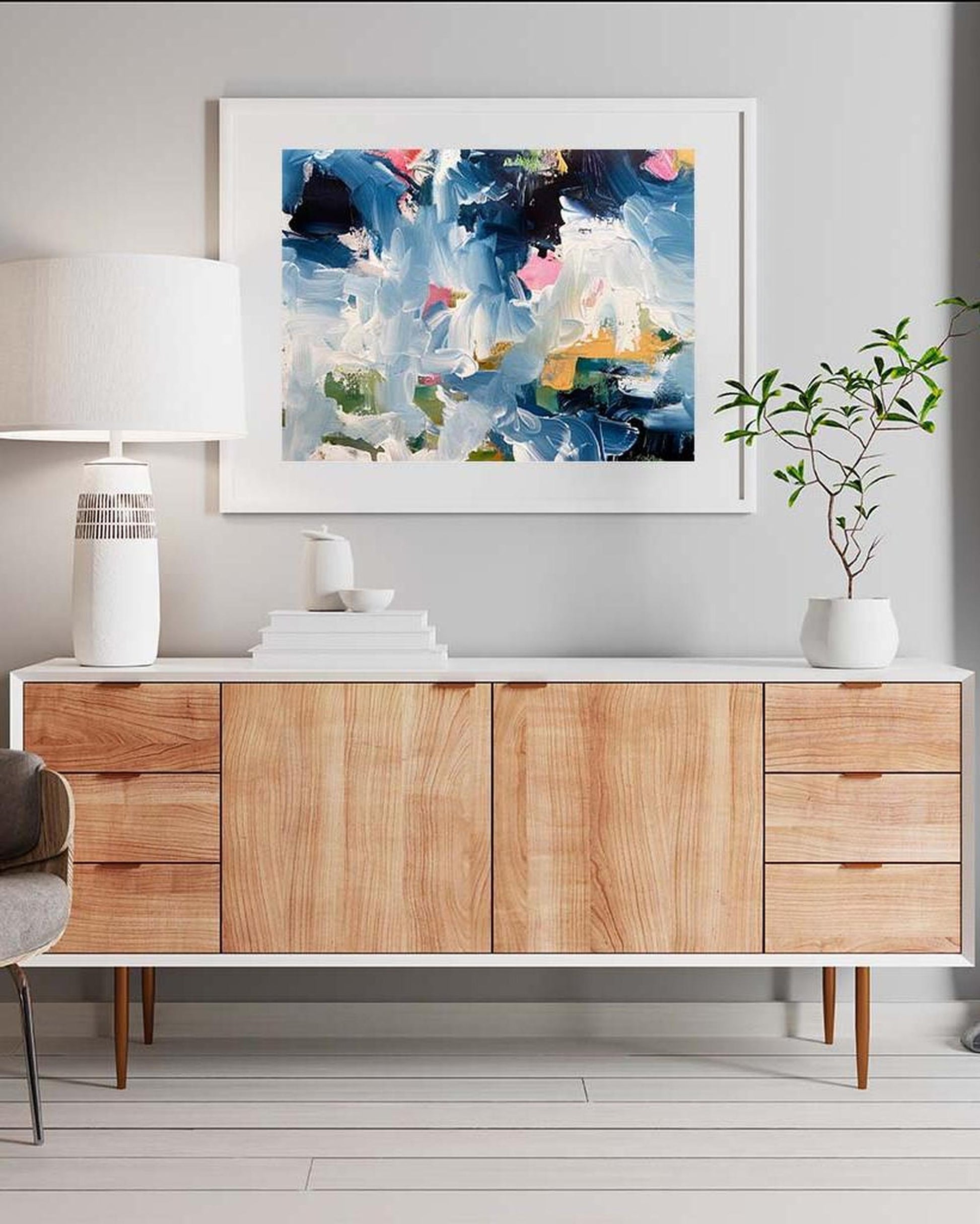Wooden sideboard with abstract art above it in a modern interior setting.