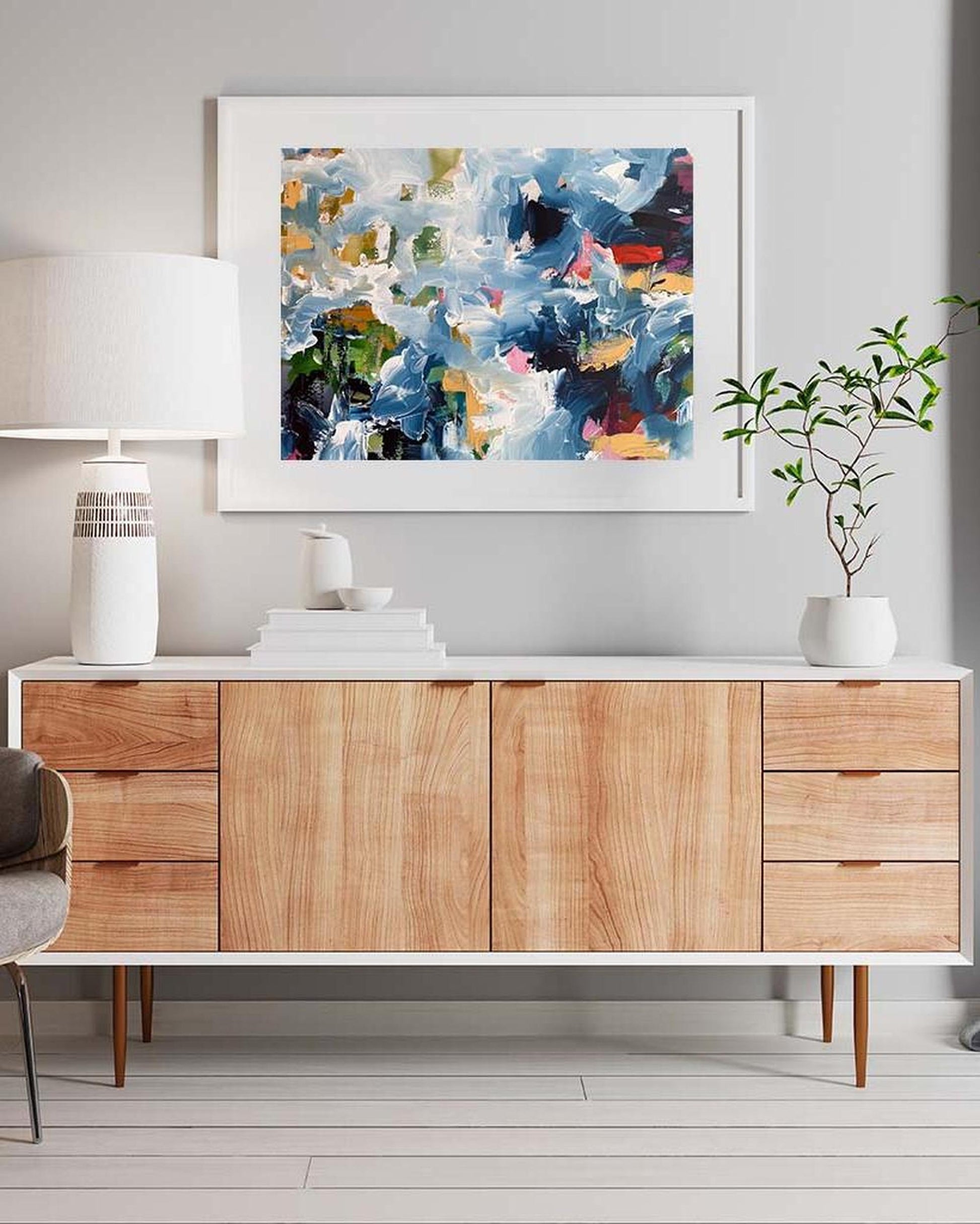Wooden sideboard with abstract art above it in a modern interior setting.