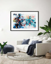 Framed abstract painting on a wall above a white sofa in a living room.