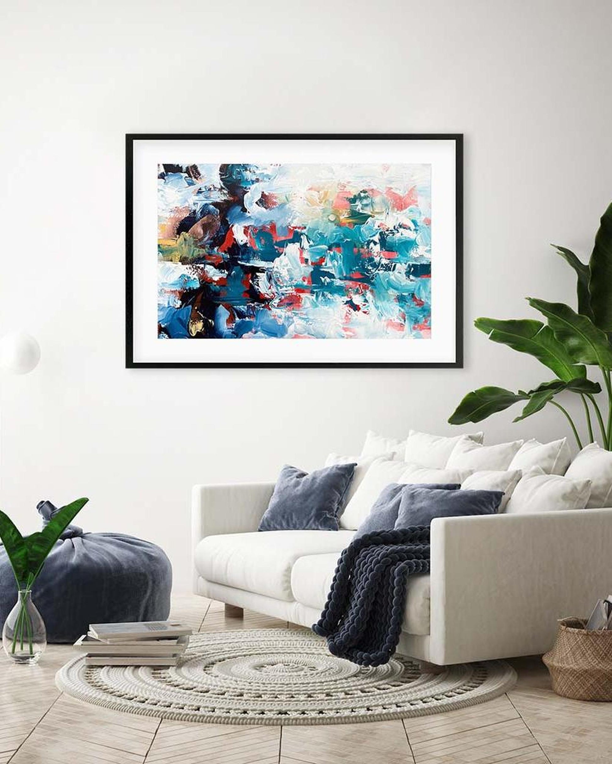 Framed abstract painting on a wall above a white sofa in a living room.