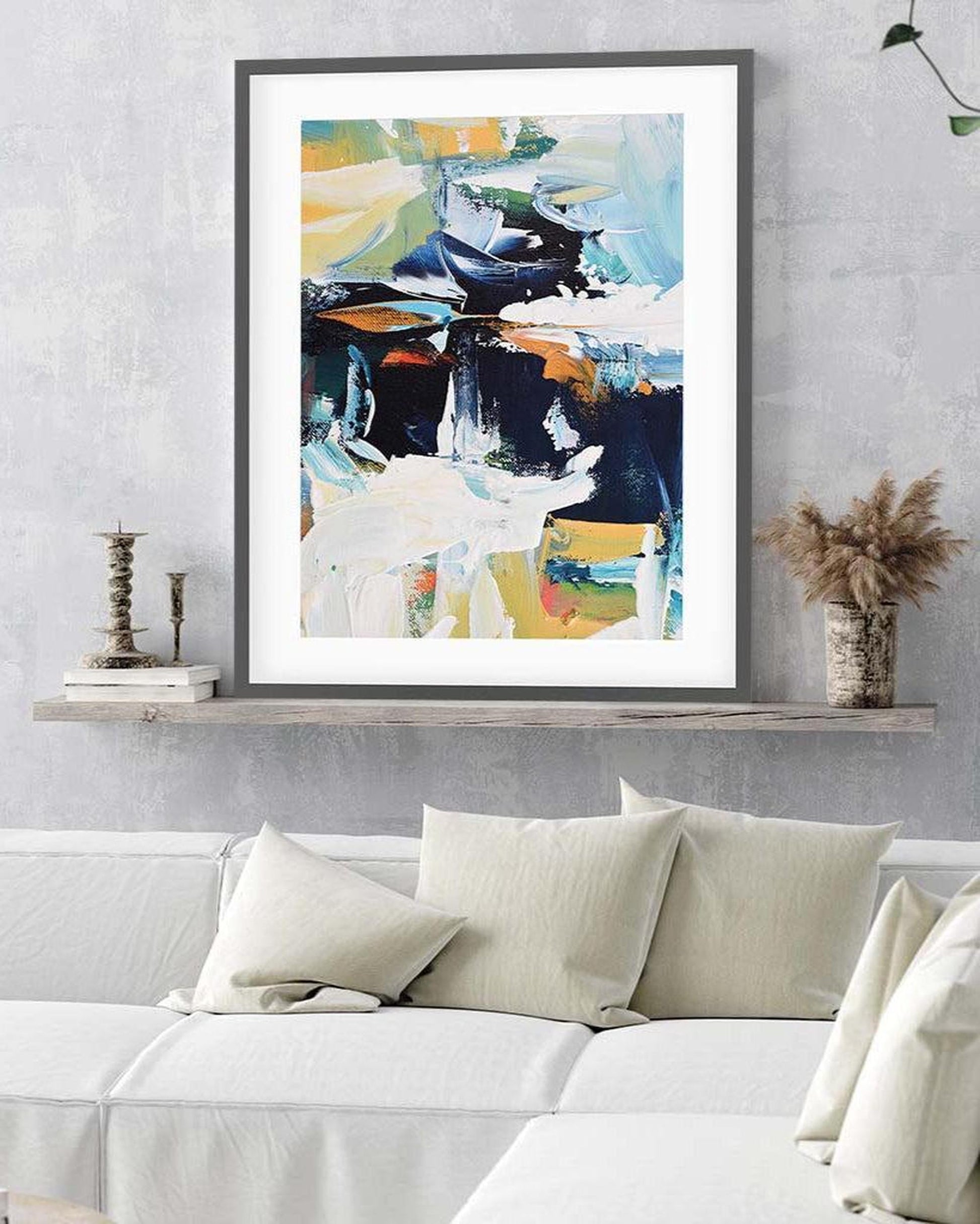 Framed abstract art print on a wall above a bed in a bedroom setting.