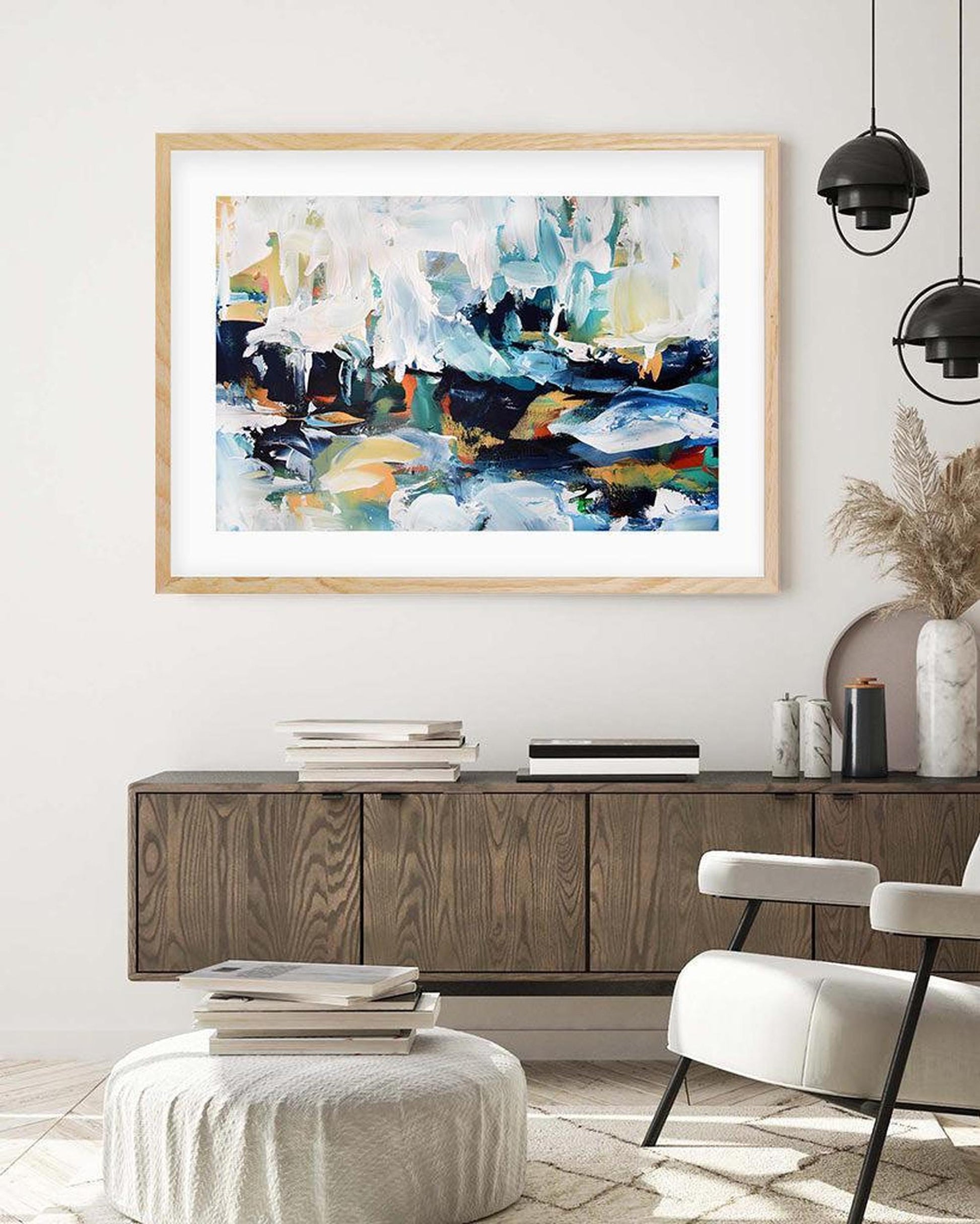 Abstract painting in a wooden frame on a wall above a wooden console table in a living room.