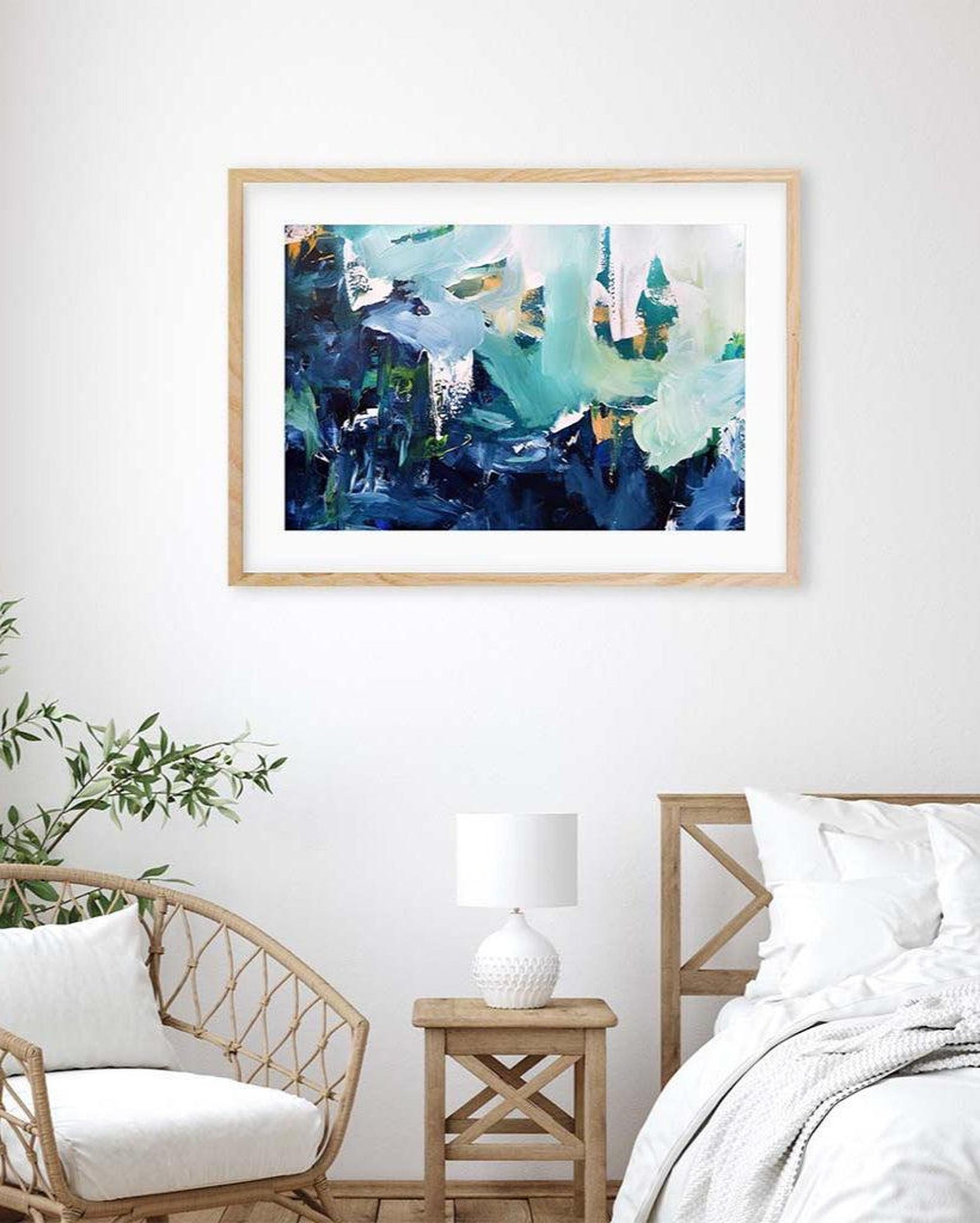Framed abstract artwork on a wall above a bed in a bedroom setting.