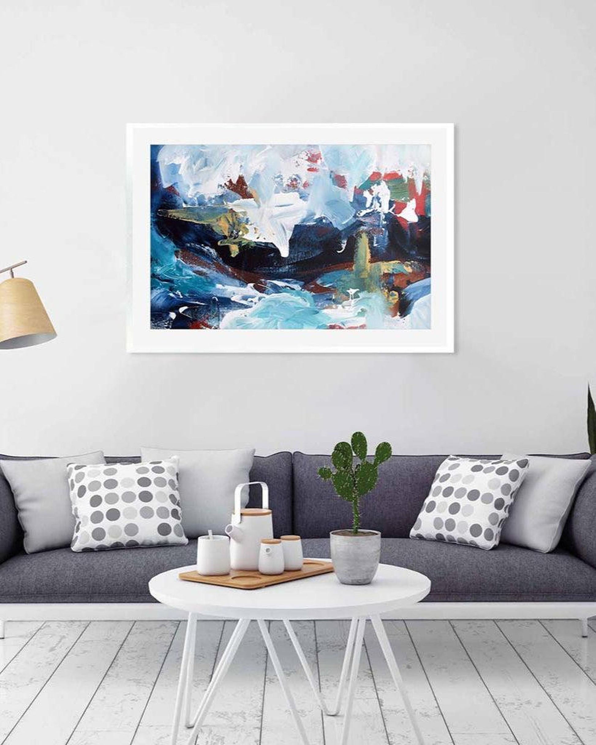 Framed abstract painting on a wall above a sofa with decorative items.