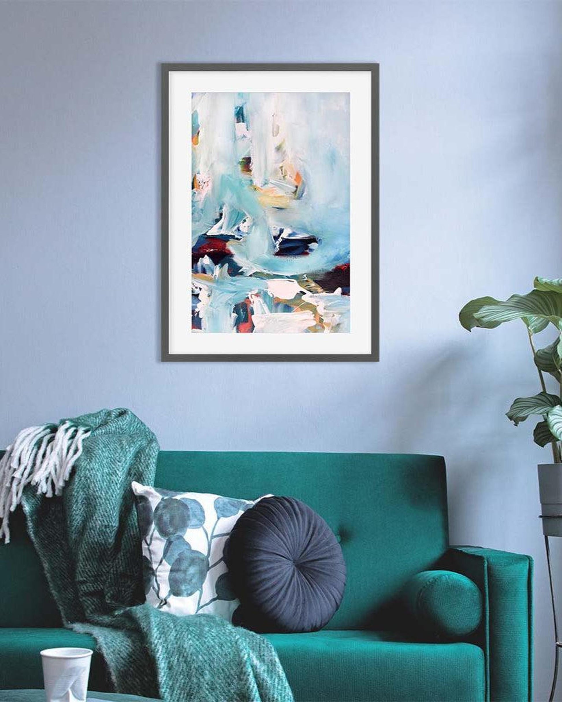 Framed abstract art piece on a wall above a green sofa with decorative pillows.