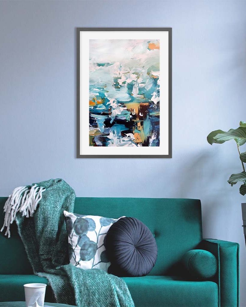 Framed abstract art on a wall above a green sofa with decorative pillows.