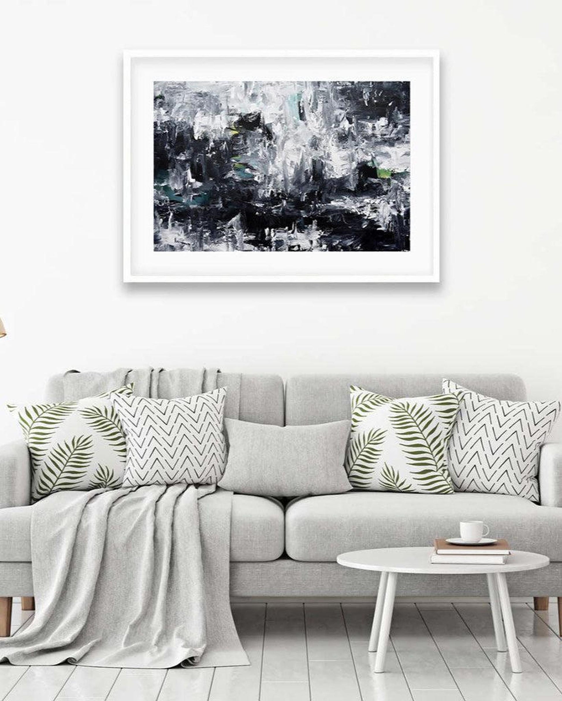 Gray sofa with decorative pillows and a coffee table, featuring a framed abstract art print on the wall.