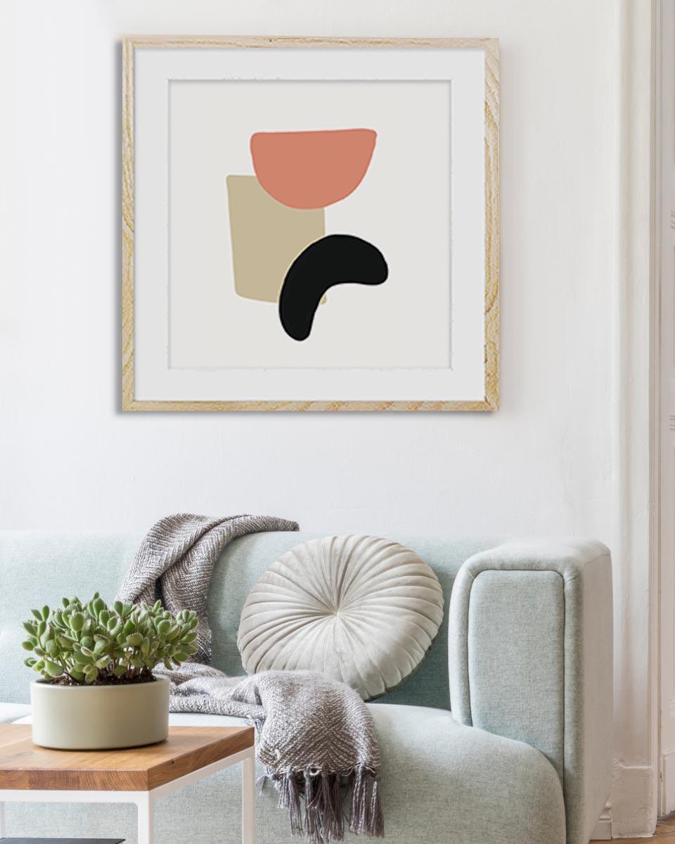 Abstract art print on a wall above a sofa with decorative pillows and a plant.