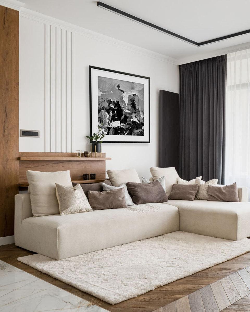 Modern living room with a beige sectional sofa, decorative pillows, and a framed artwork on the wall.