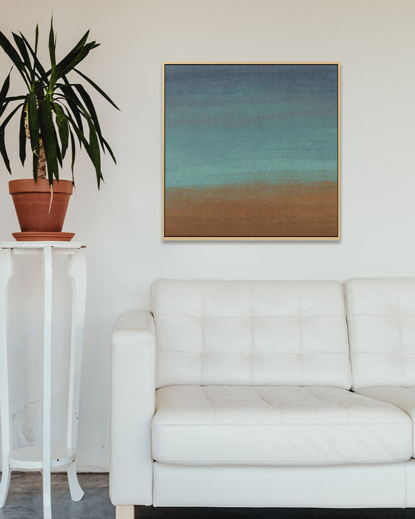 White sofa in a living room with a plant and abstract painting on the wall.