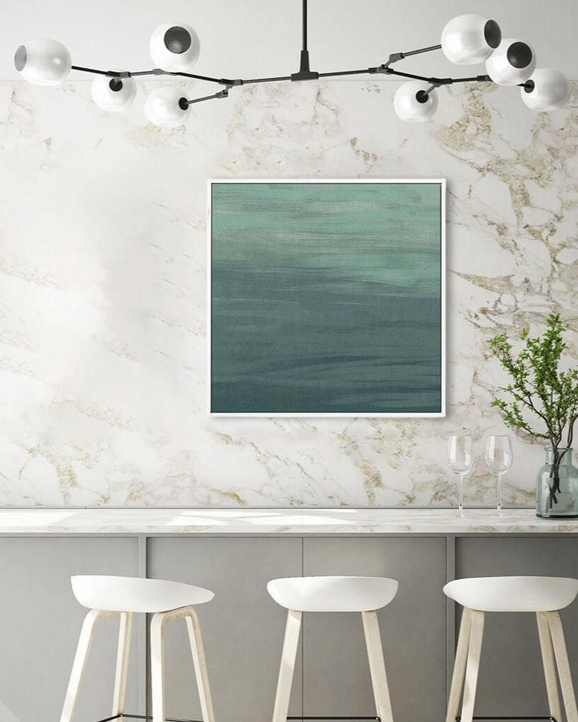 Modern kitchen with marble wall, framed artwork, and white stools.