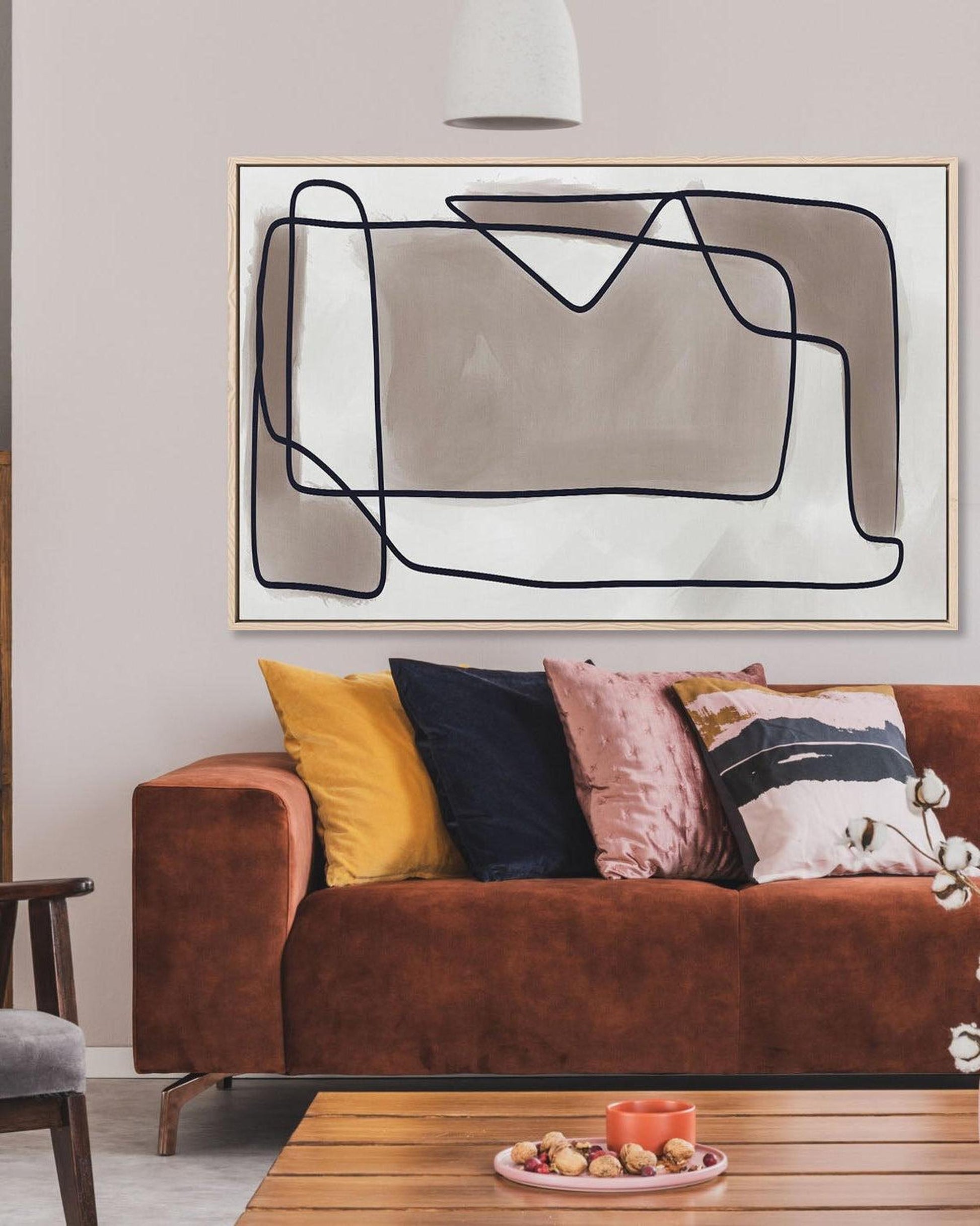 Living room with a brown sofa, colorful pillows, and abstract art on the wall.