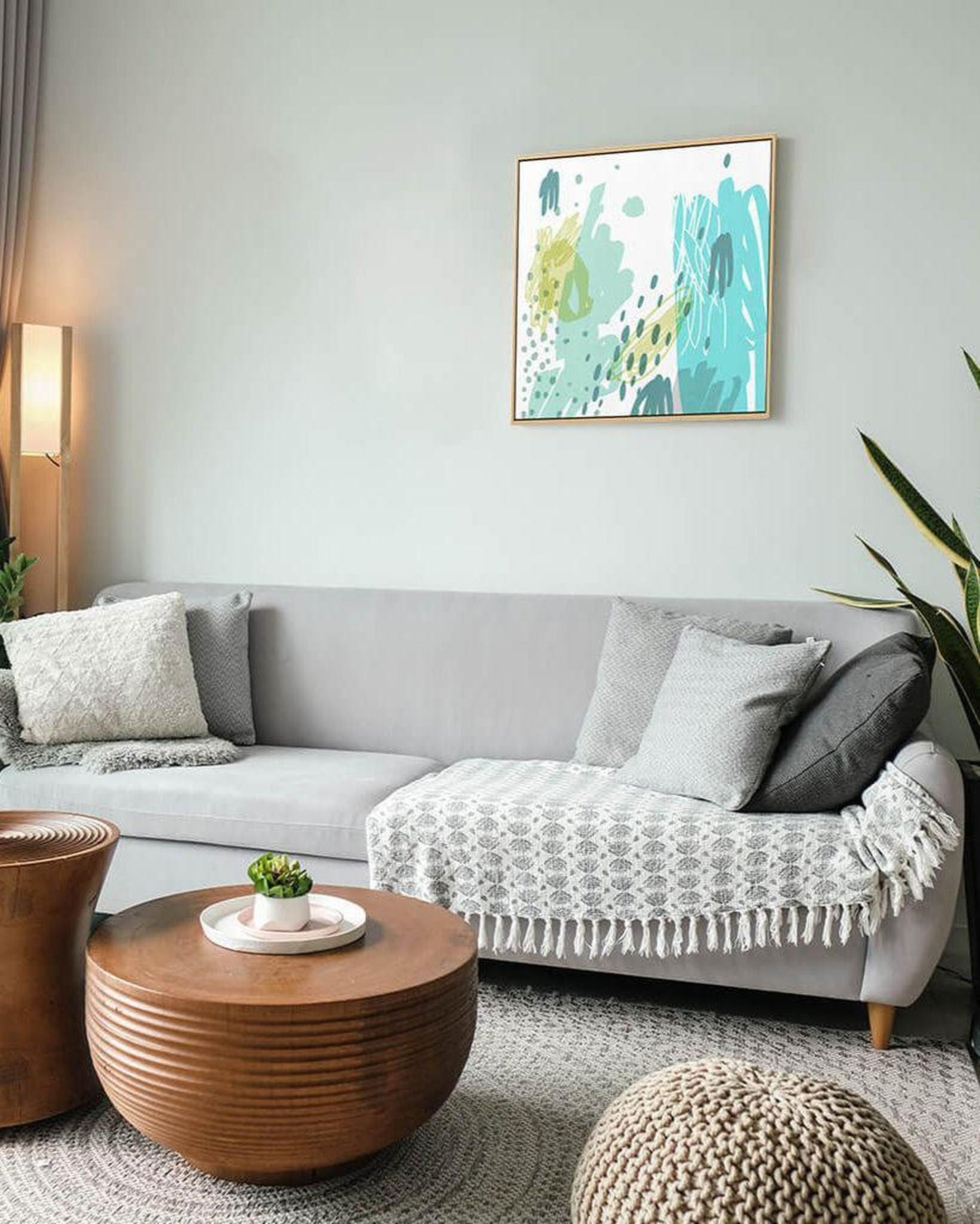 Living room with a gray sofa, wooden coffee table, and abstract art on the wall.