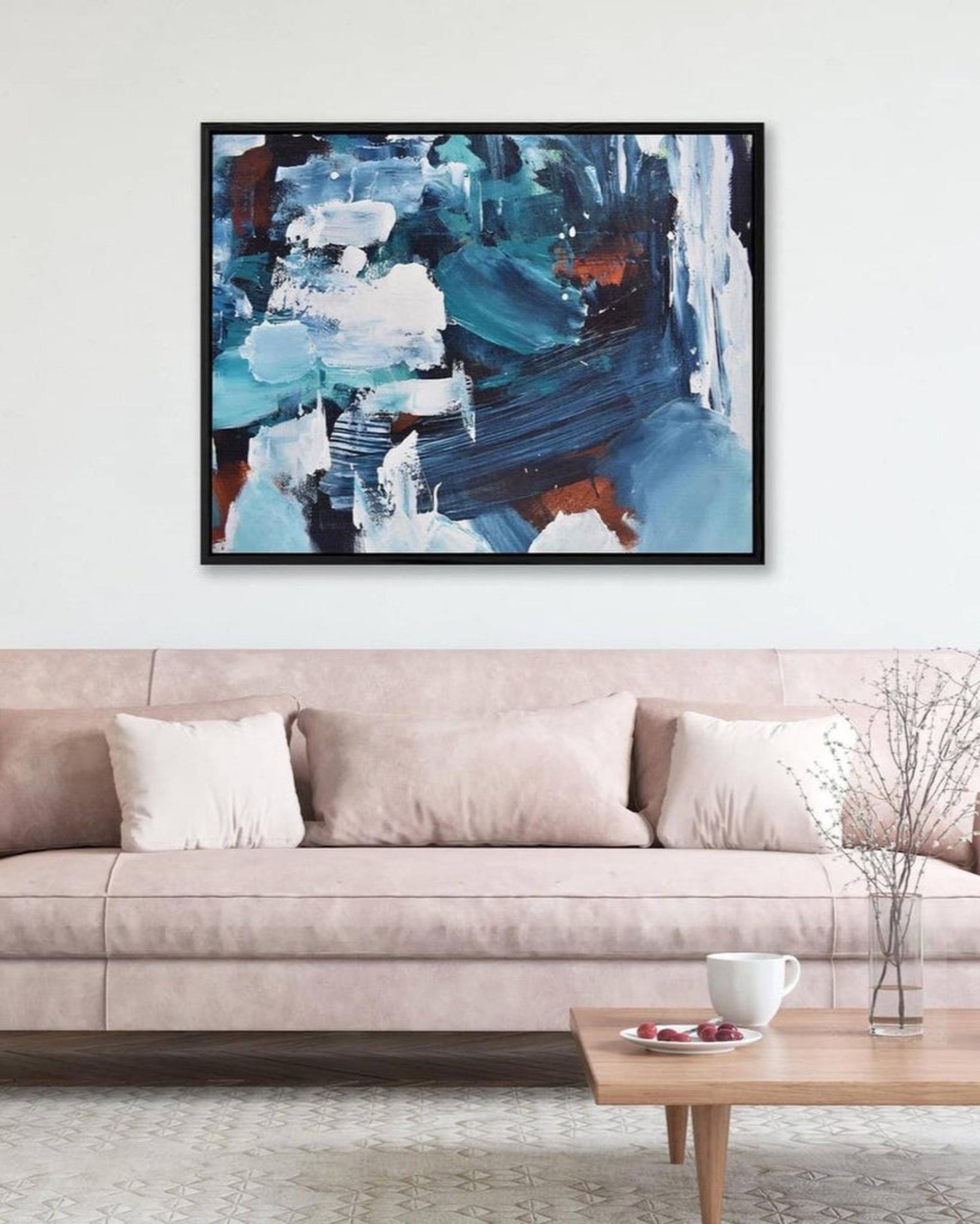Abstract painting on a wall above a beige sofa in a living room.