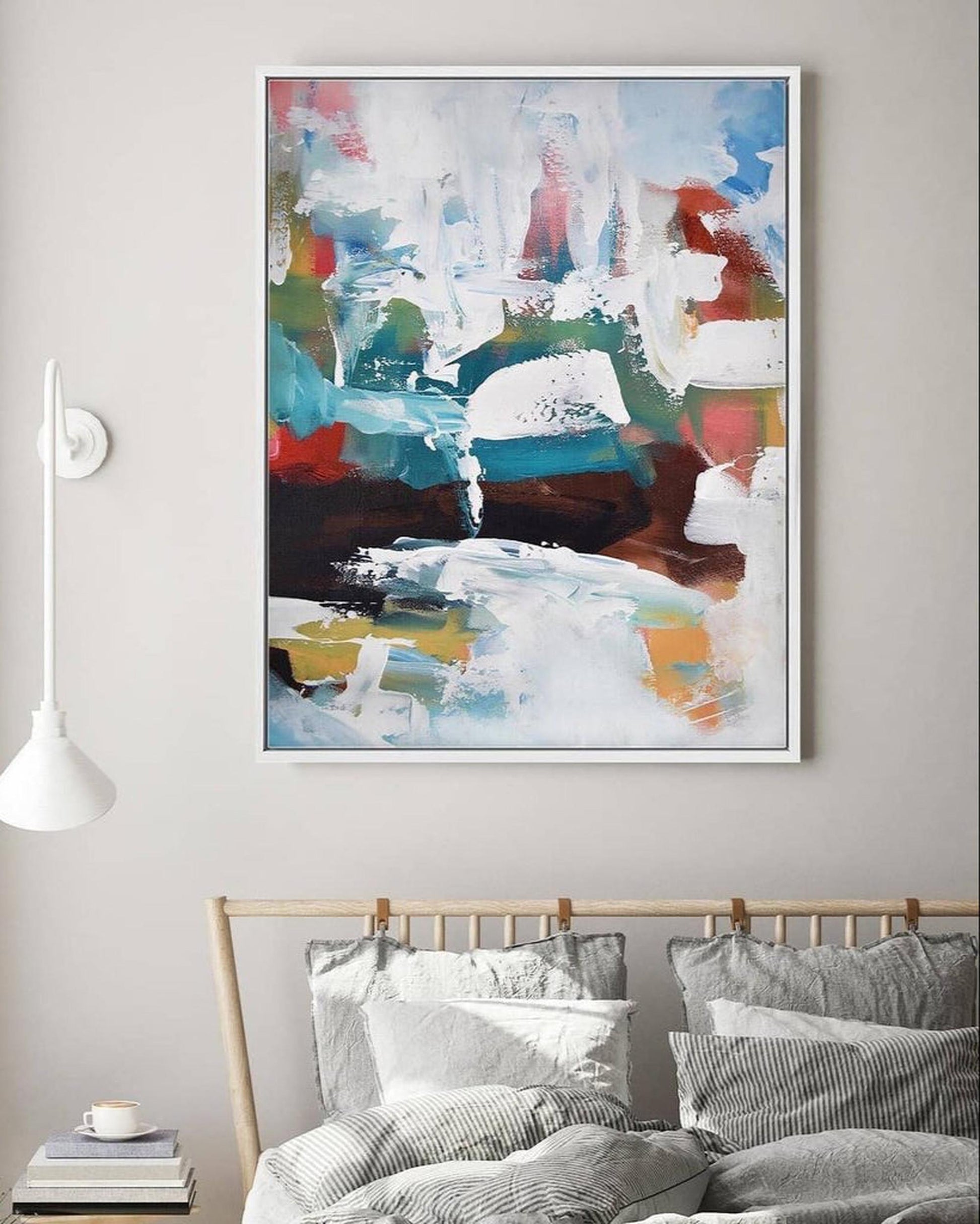Abstract painting on a wall above a bed with striped bedding.