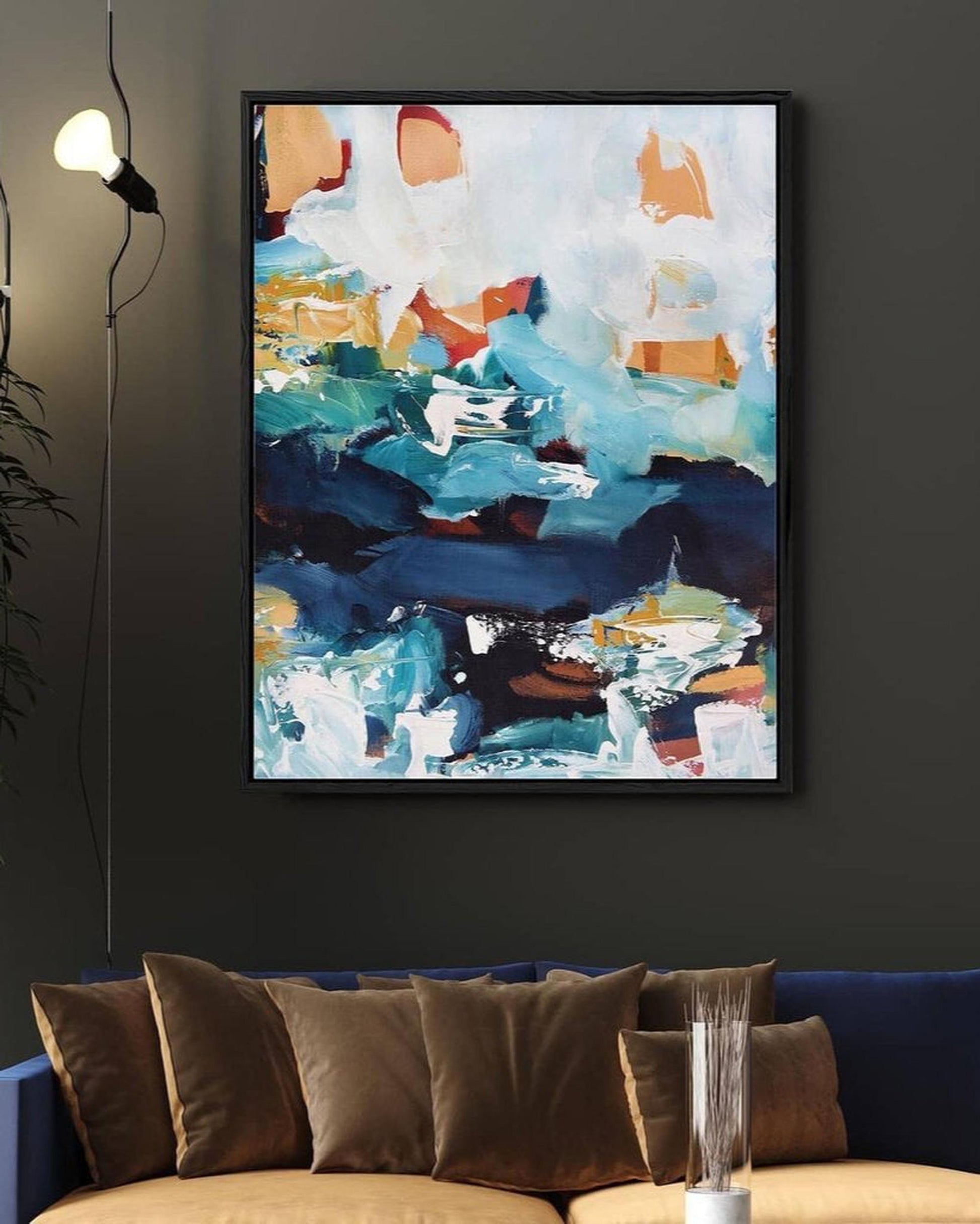 Abstract painting on a dark wall above a sofa with brown cushions.