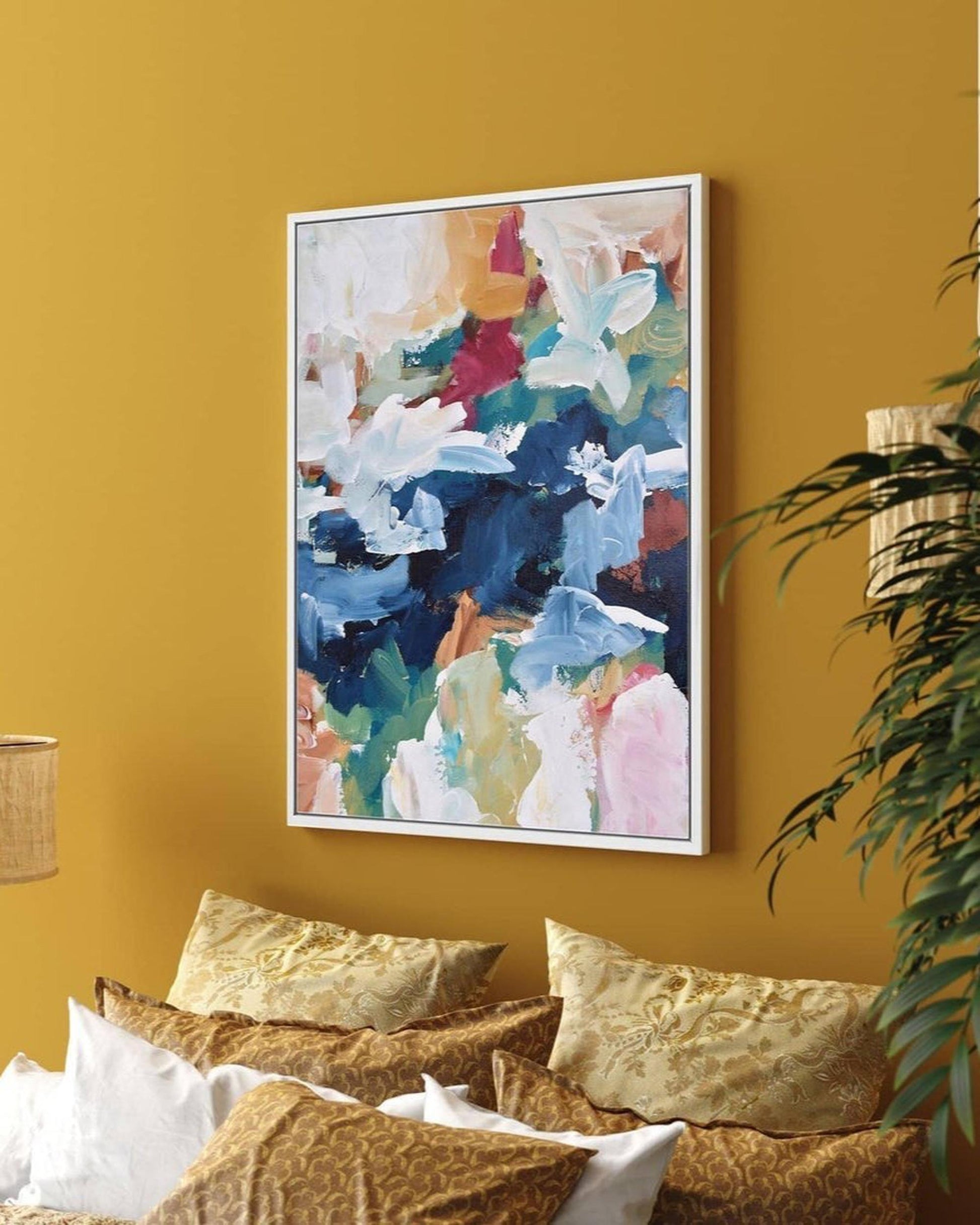 Colorful abstract painting on a yellow wall with a couch and plant in the foreground