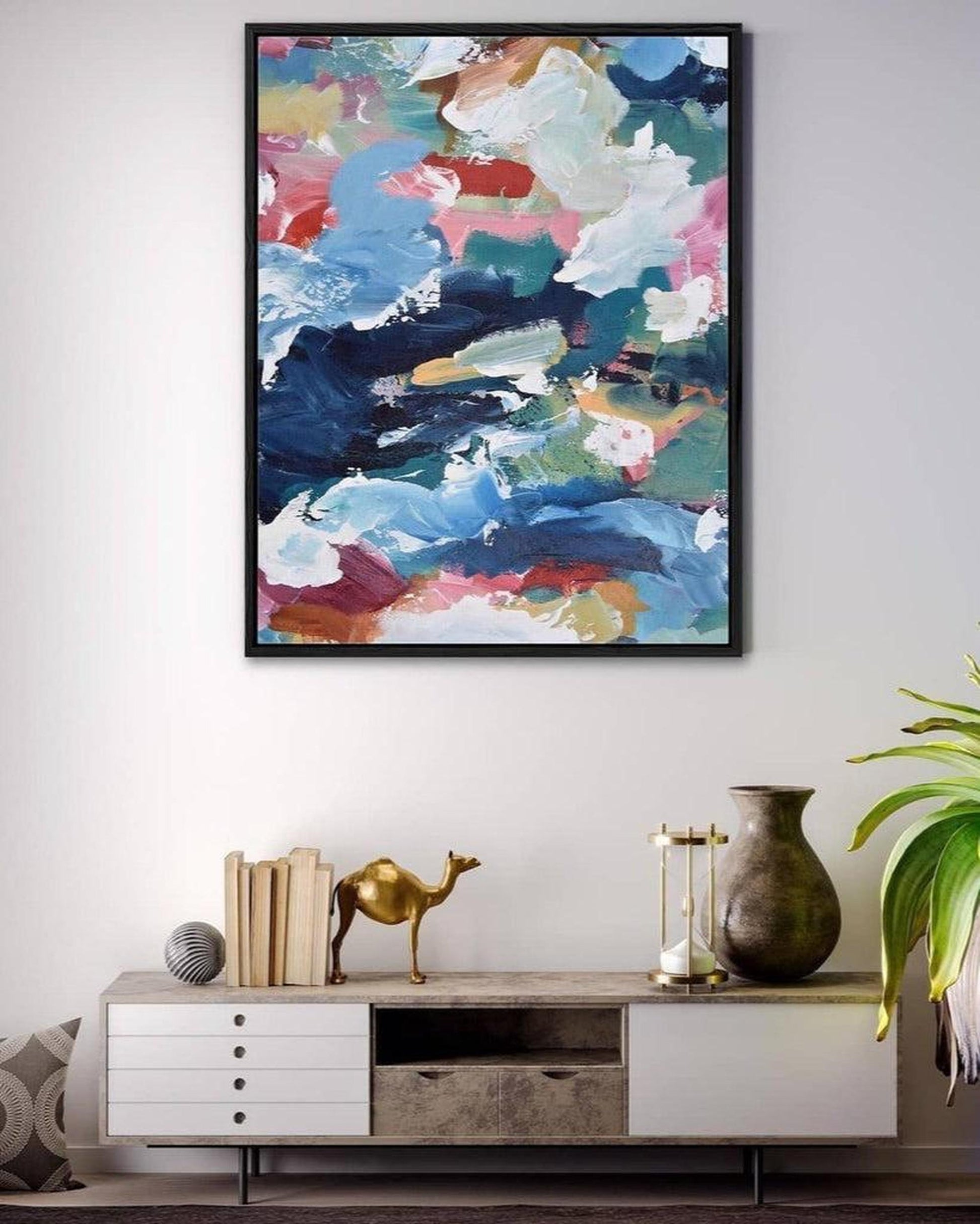 Abstract painting on a wall above a console table with decorative items.