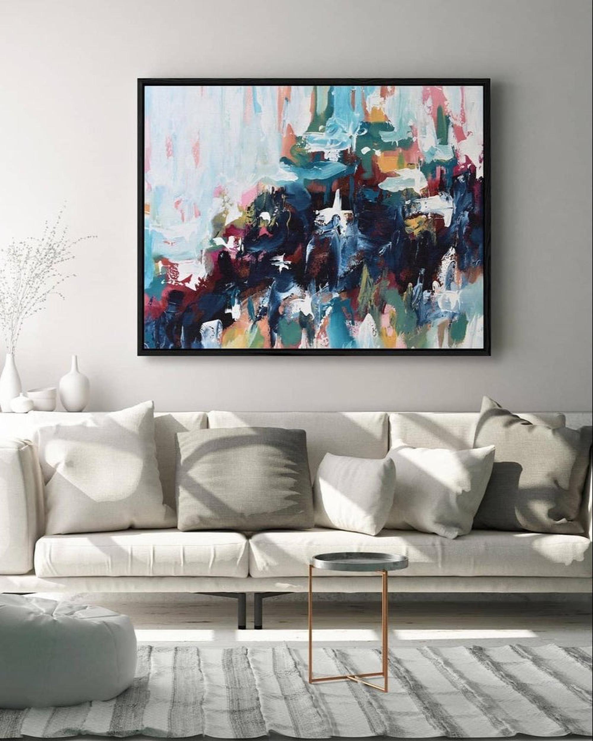 Abstract painting on a wall above a white sofa in a living room.