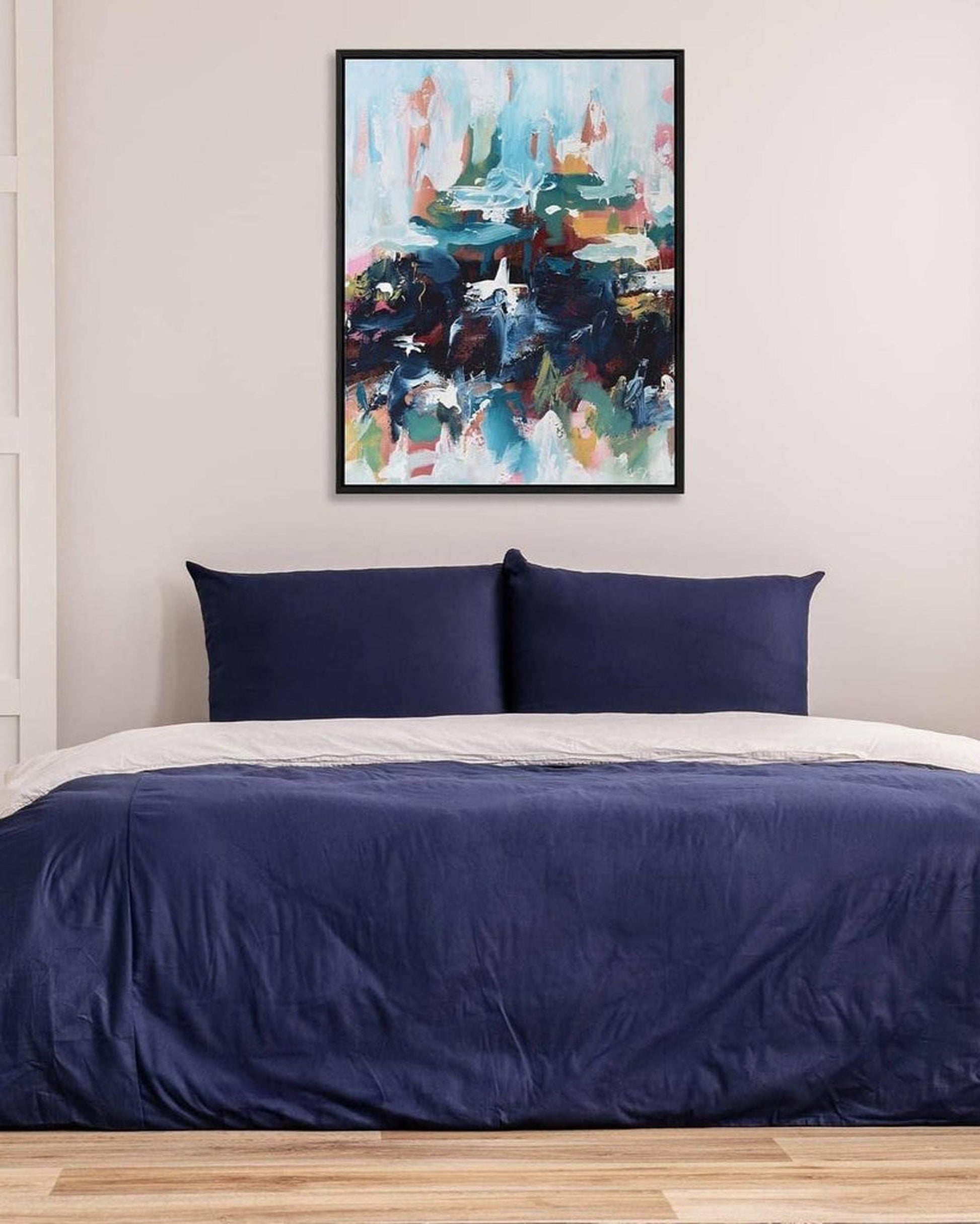 Bedroom with navy bedding and abstract art on the wall