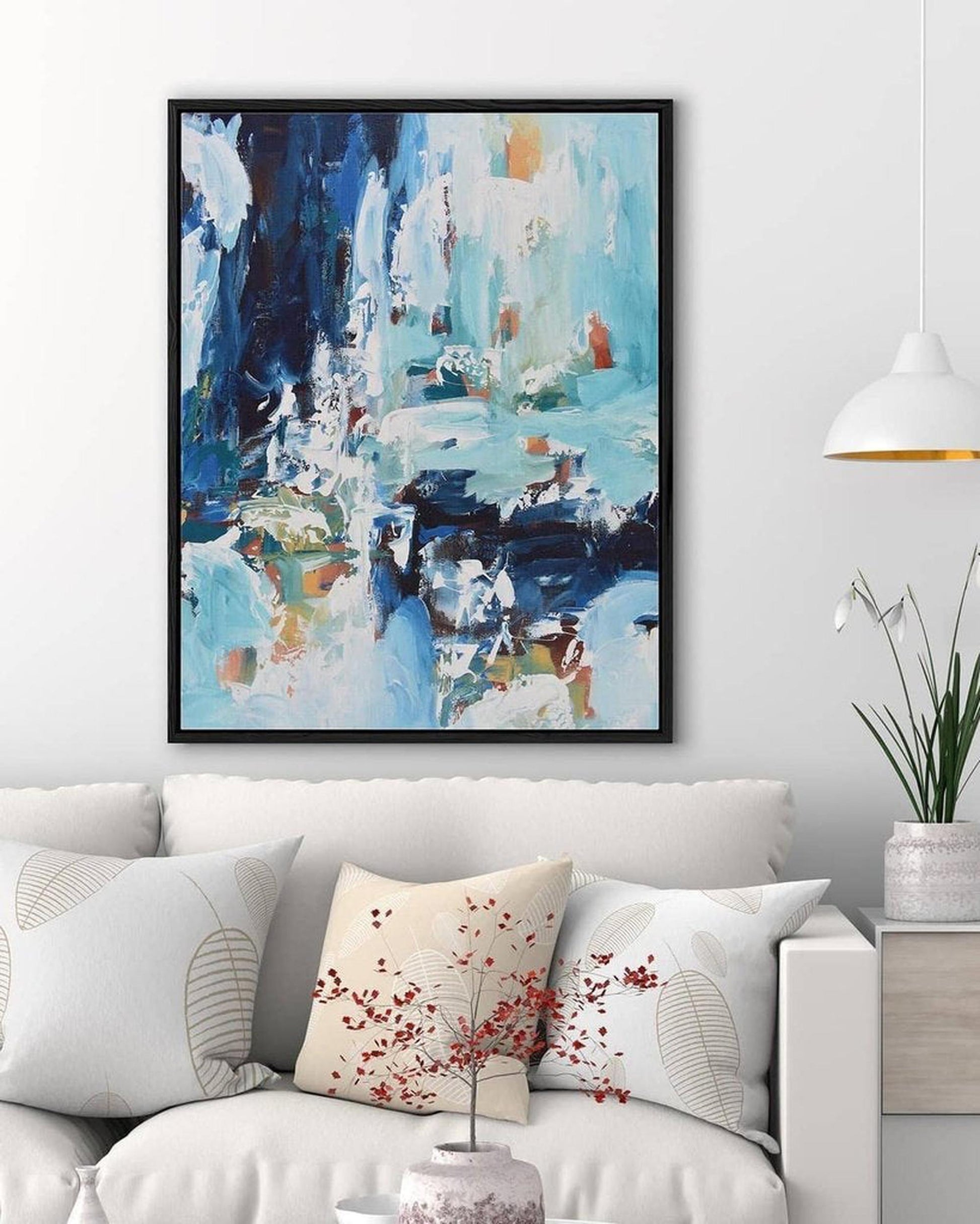 Abstract painting on a wall above a sofa with decorative pillows.