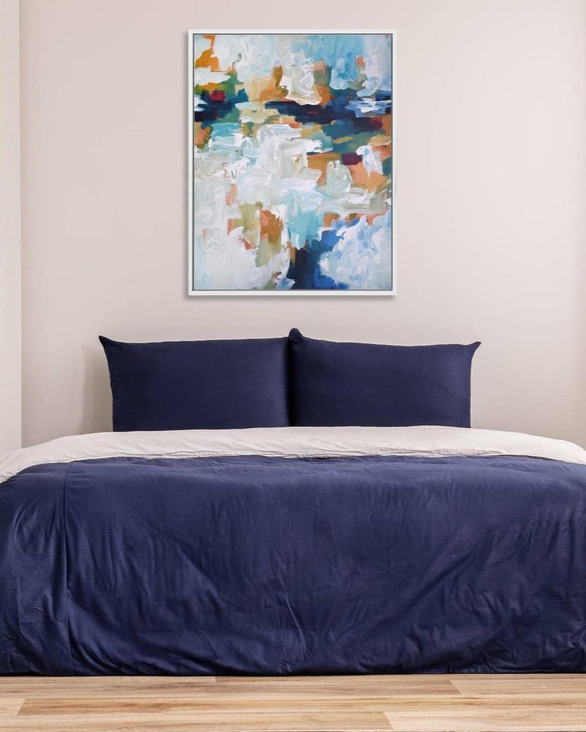 Bedroom with blue bedding and abstract art on the wall
