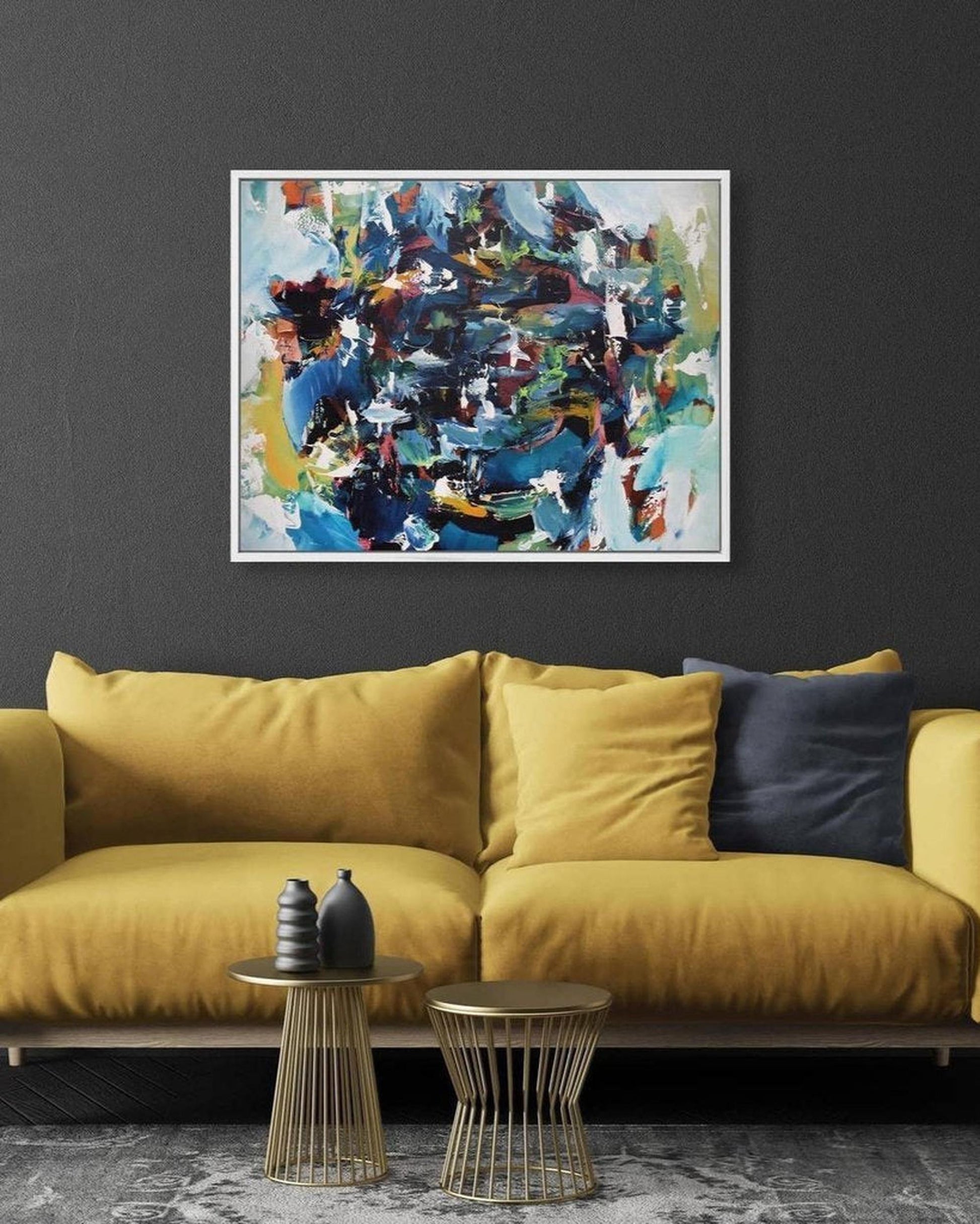 Yellow sofa with decorative pillows in a room with a colorful abstract painting on the wall.